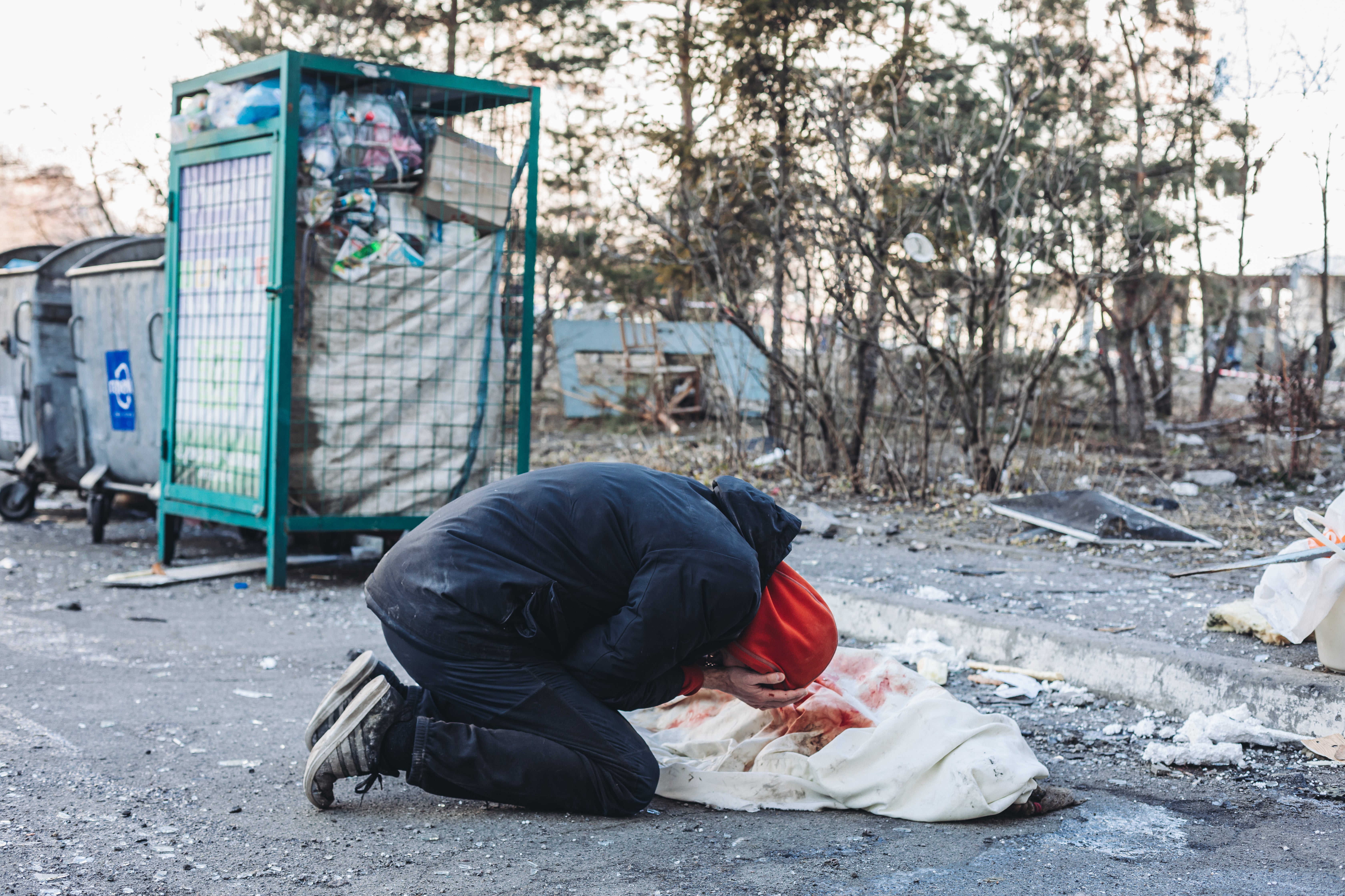 A man cries in front of the body of his mother, who died after a projectile hit a house in Kyiv