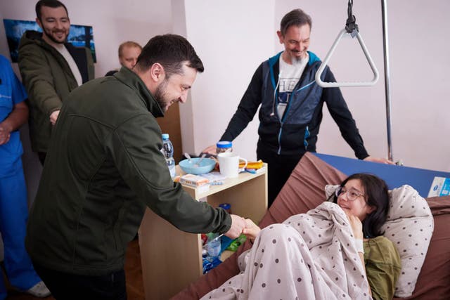 <p>In this photo provided by the Ukrainian Presidential Press Office on Thursday, 17 March 2022, President Volodymyr Zelenskyy, shakes hands with a wounded Kateryna Vlasenko, 16, a refugee from Vorzel who covered her junior brother with her body during Russian shelling as they ran from their home town in a hospital in Kyiv, Ukraine</p>