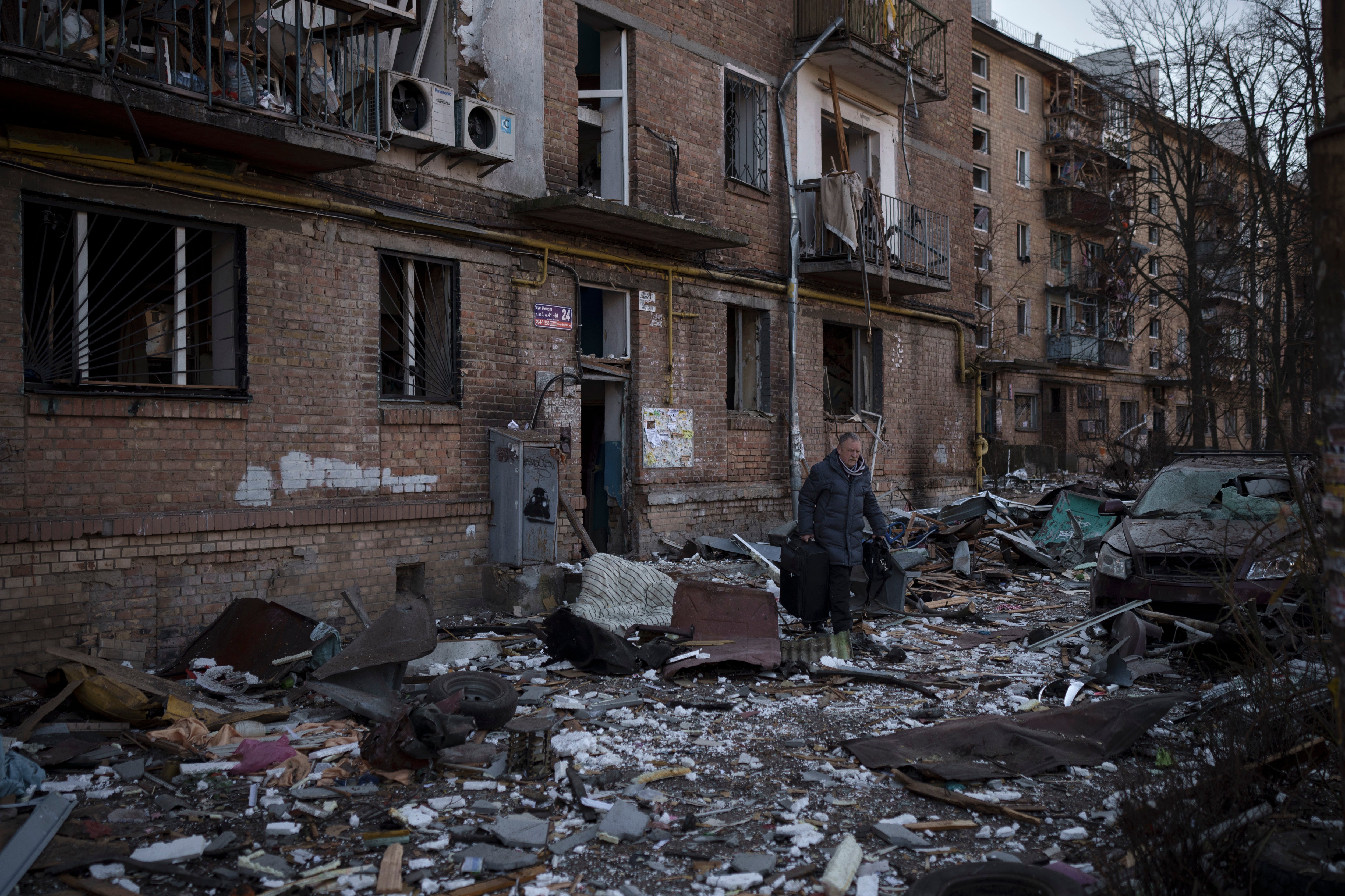A resident carries a suitcase with his belongings after his building was heavily damaged by bombing in Kyiv, Ukraine.