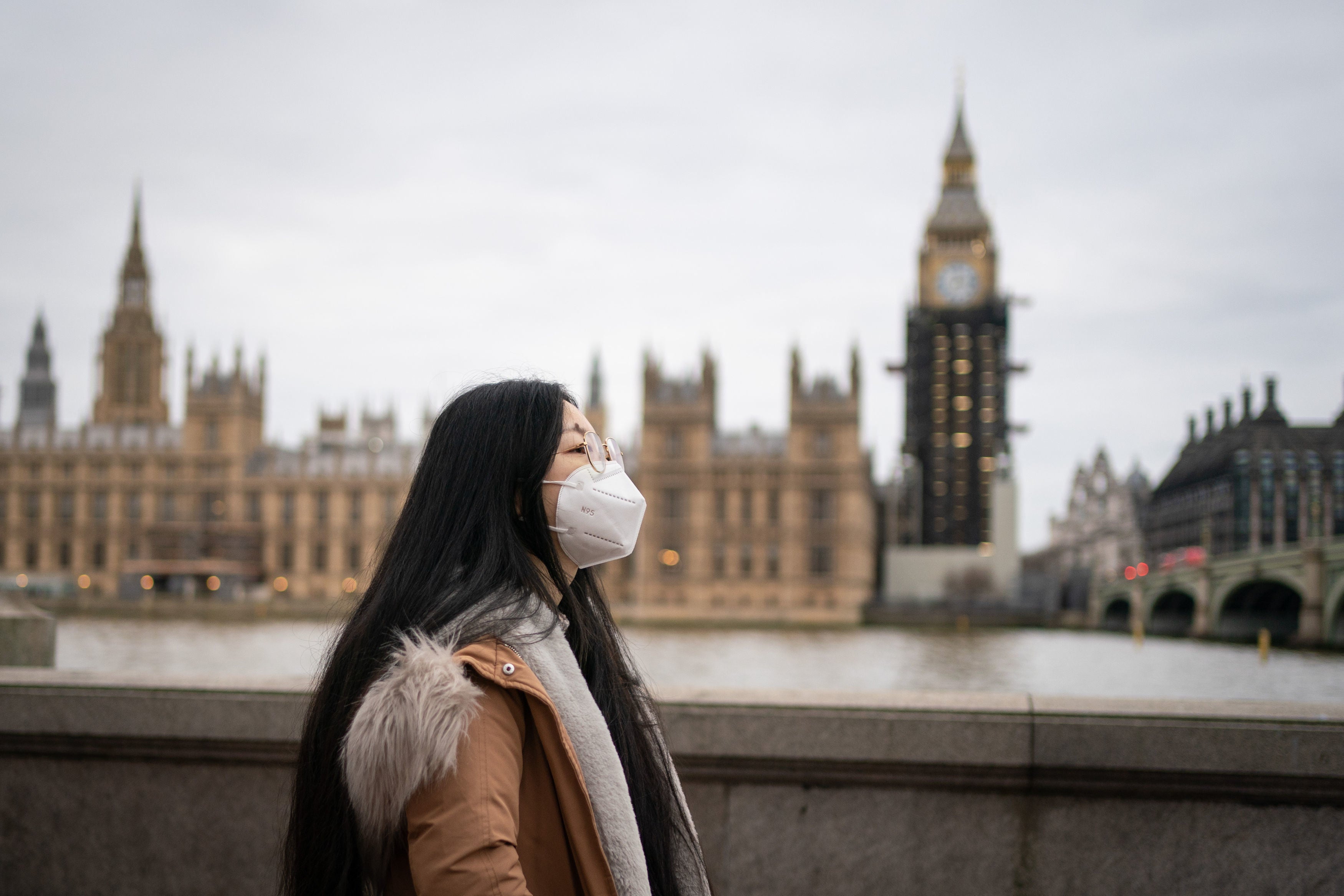 A woman wearing a face mask walking near the Houses of Parliament