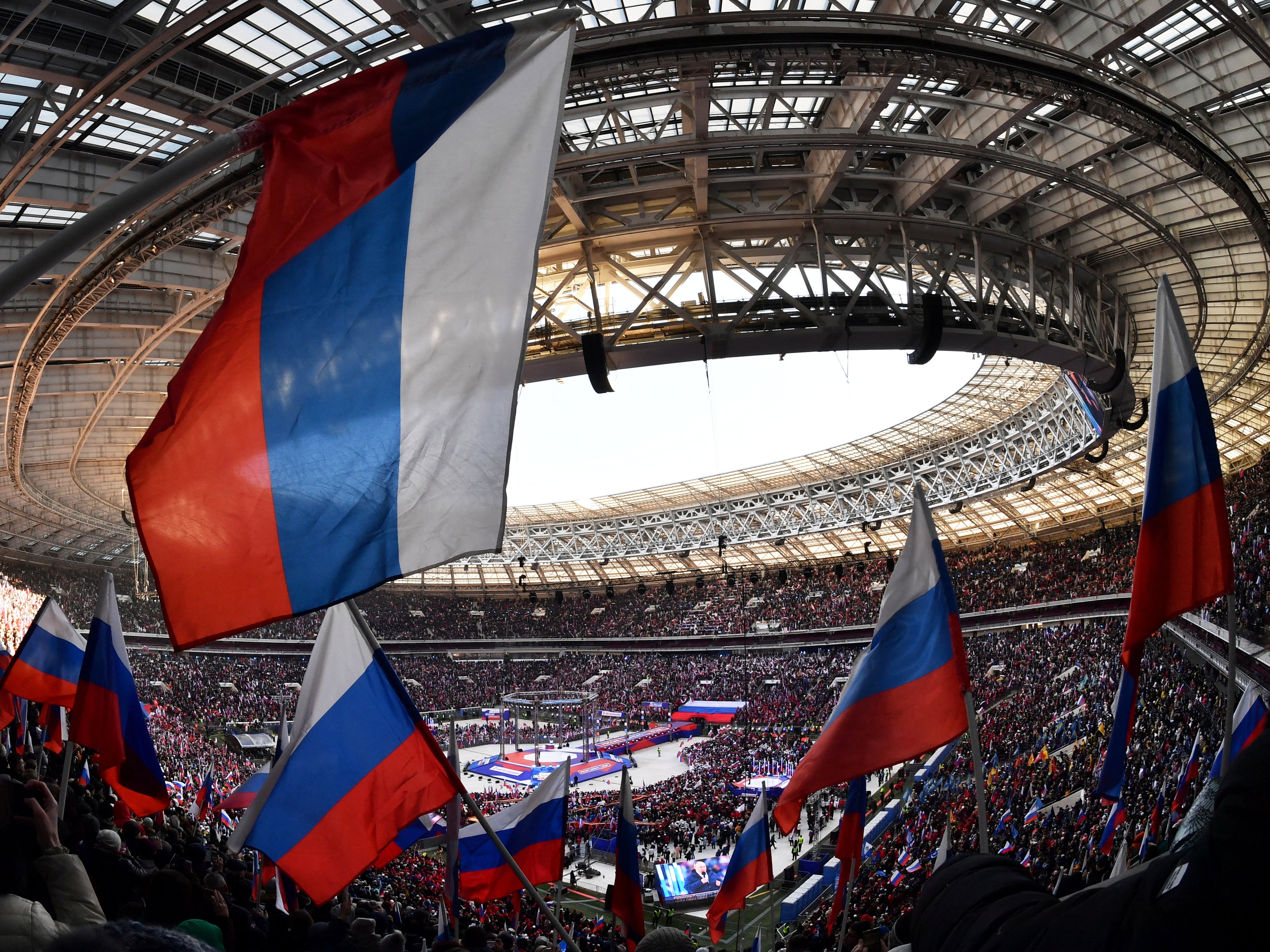 People wave Russian flags during a concert marking the eighth anniversary of Russia's annexation of Crimea