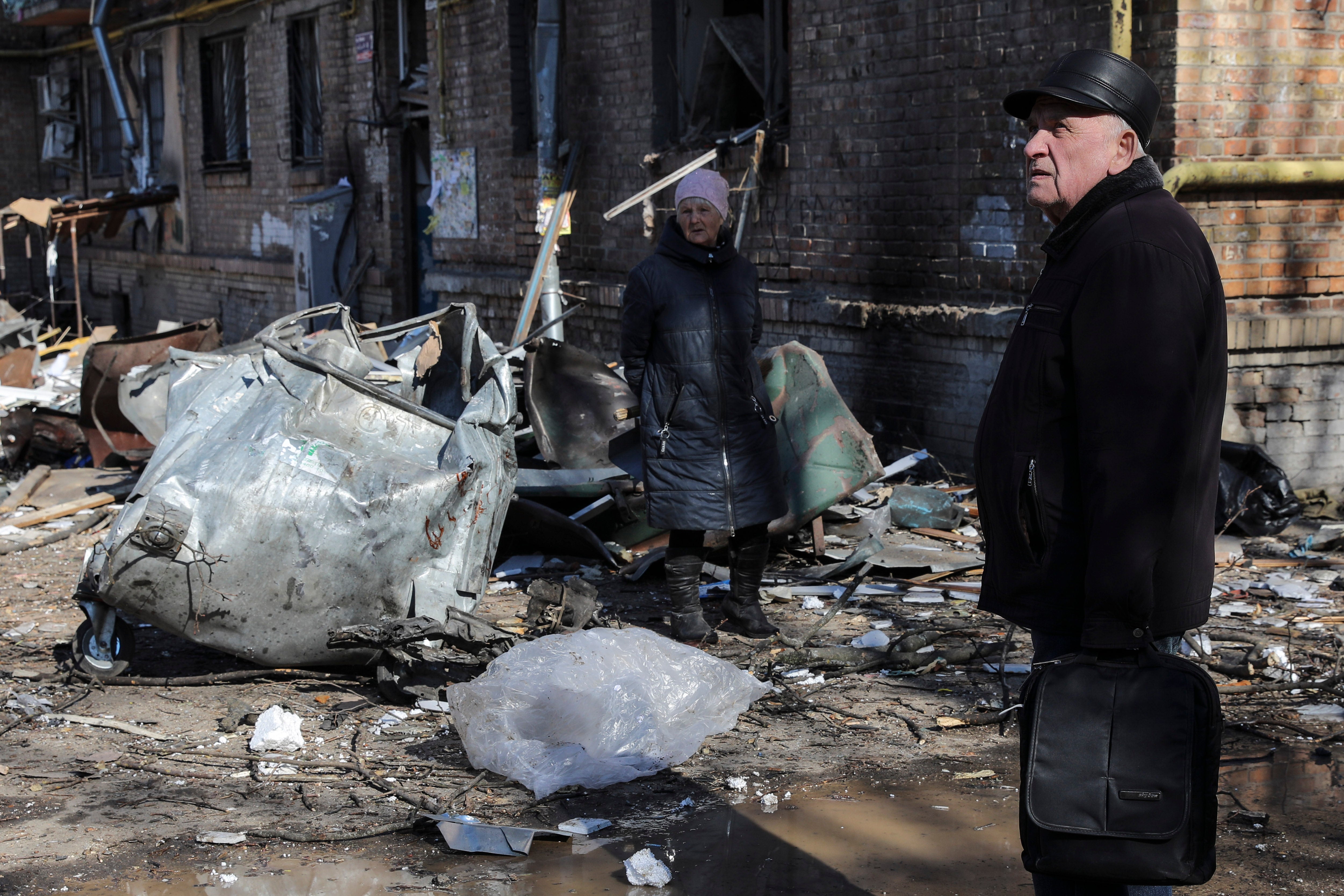 A man and a woman walk in the debris of buildings destroyed by shelling in Kyiv on Friday