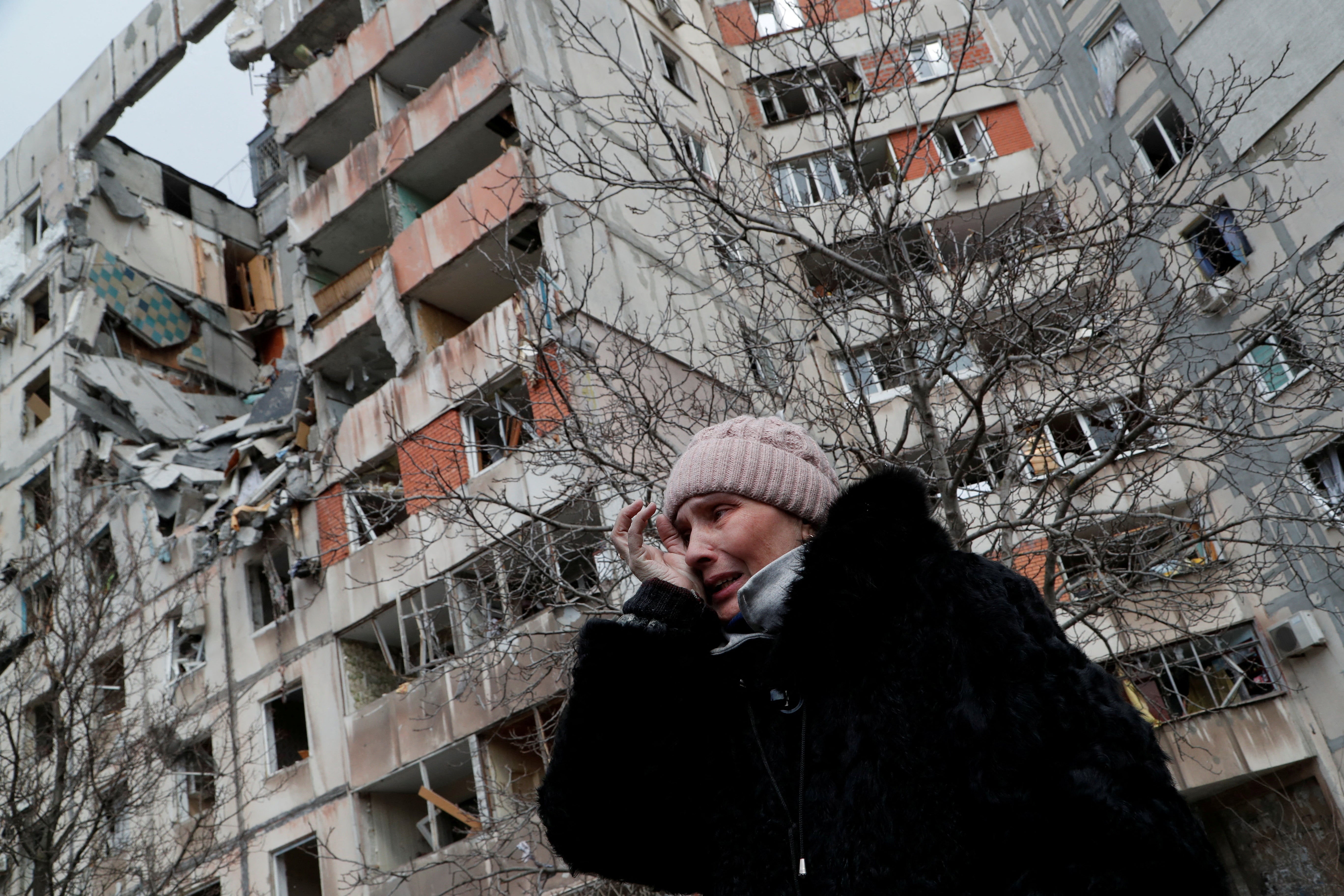 A woman reacts while speaking near a block of flats, which was destroyed during Ukraine-Russia conflict in the besieged southern port city of Mariupol