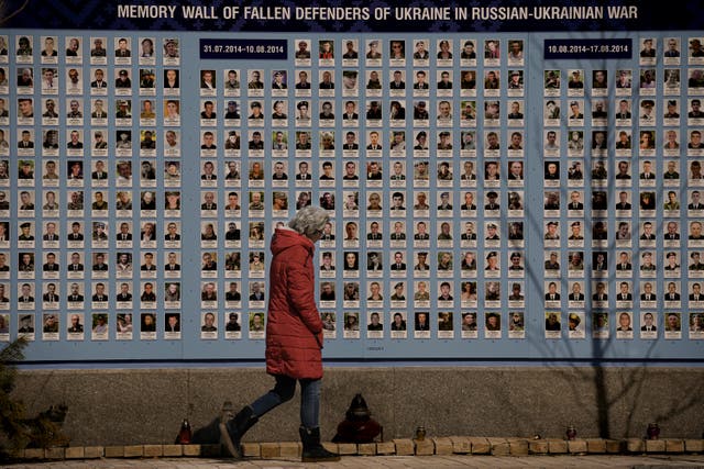 <p>A woman walks past a memorial wall, on 18 March, for all those who have lost their lives since the conflict began in Ukraine Eastern</p>