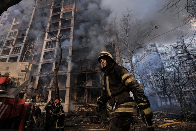 <p>A firefighter walks outside a destroyed apartment building in Kyiv, following a Russian shelling attack on 15 March </p>