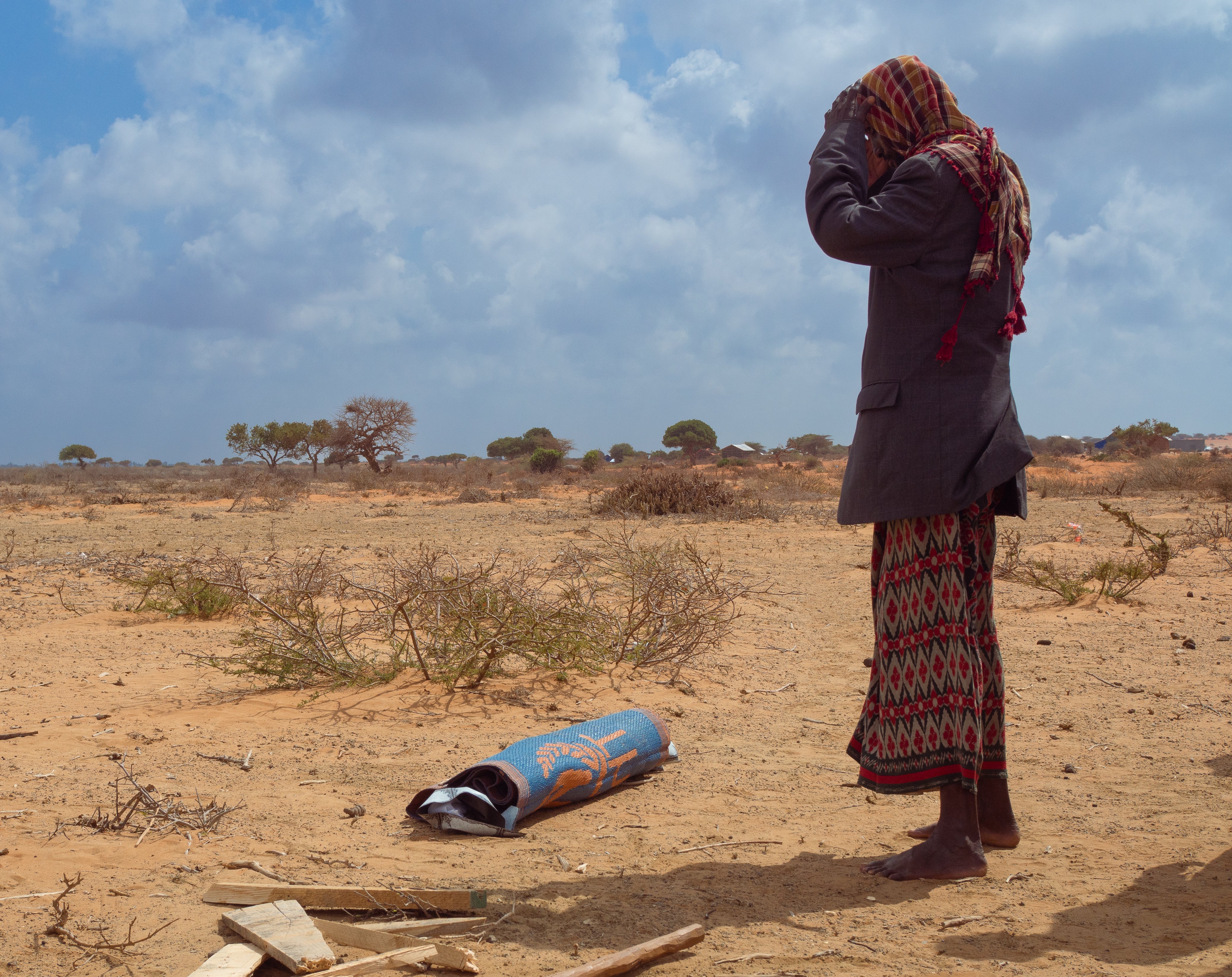 A mourner prepares for the burial of 4-year-old Ubah, whose body was wrapped in a blue and orange sleeping mat, in Jubaland, Somalia