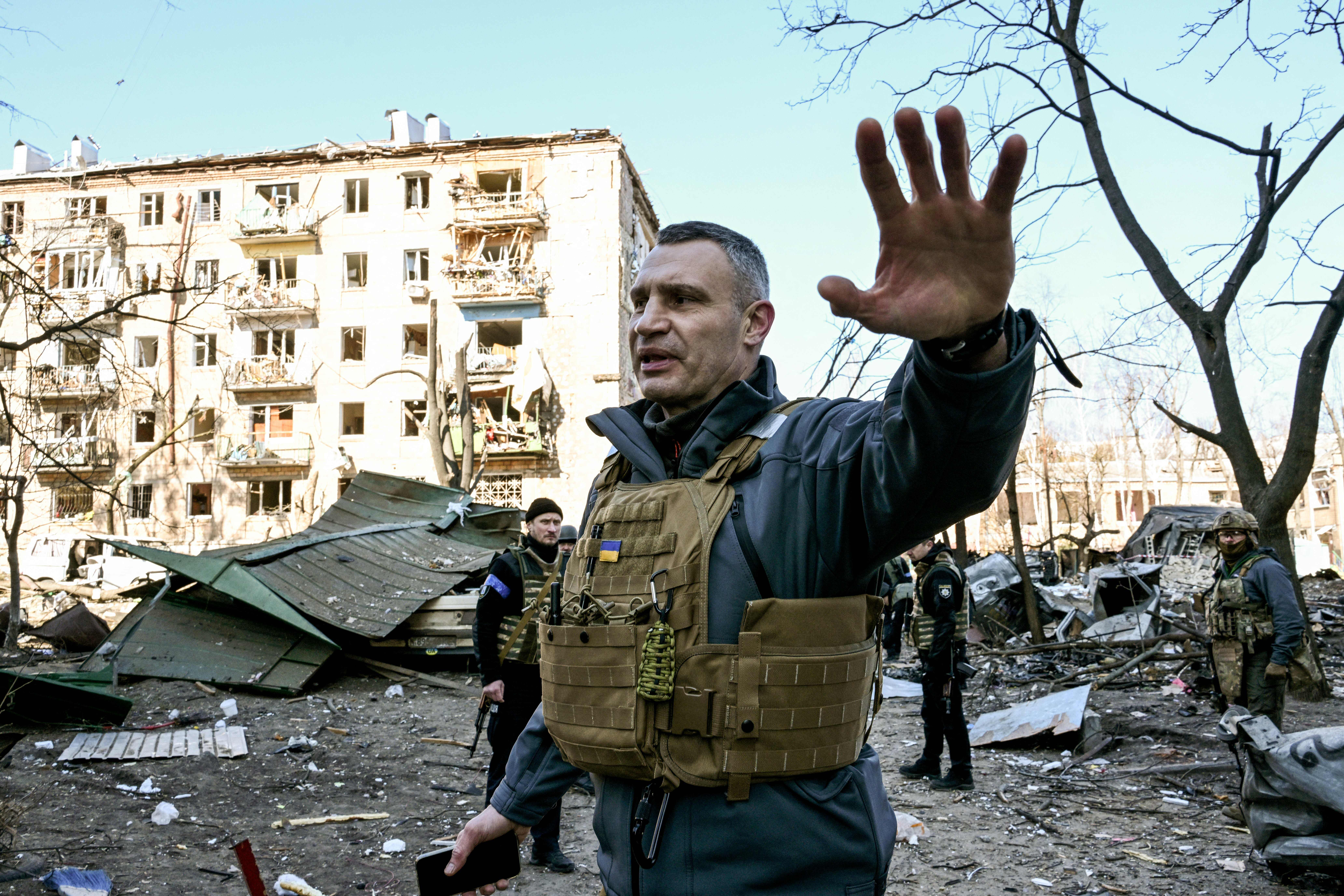 Kyiv’s mayor Vitali Klitschko holds people away from a five-storey residential building that partially collapsed after a shelling in Podil, 18 March 2022