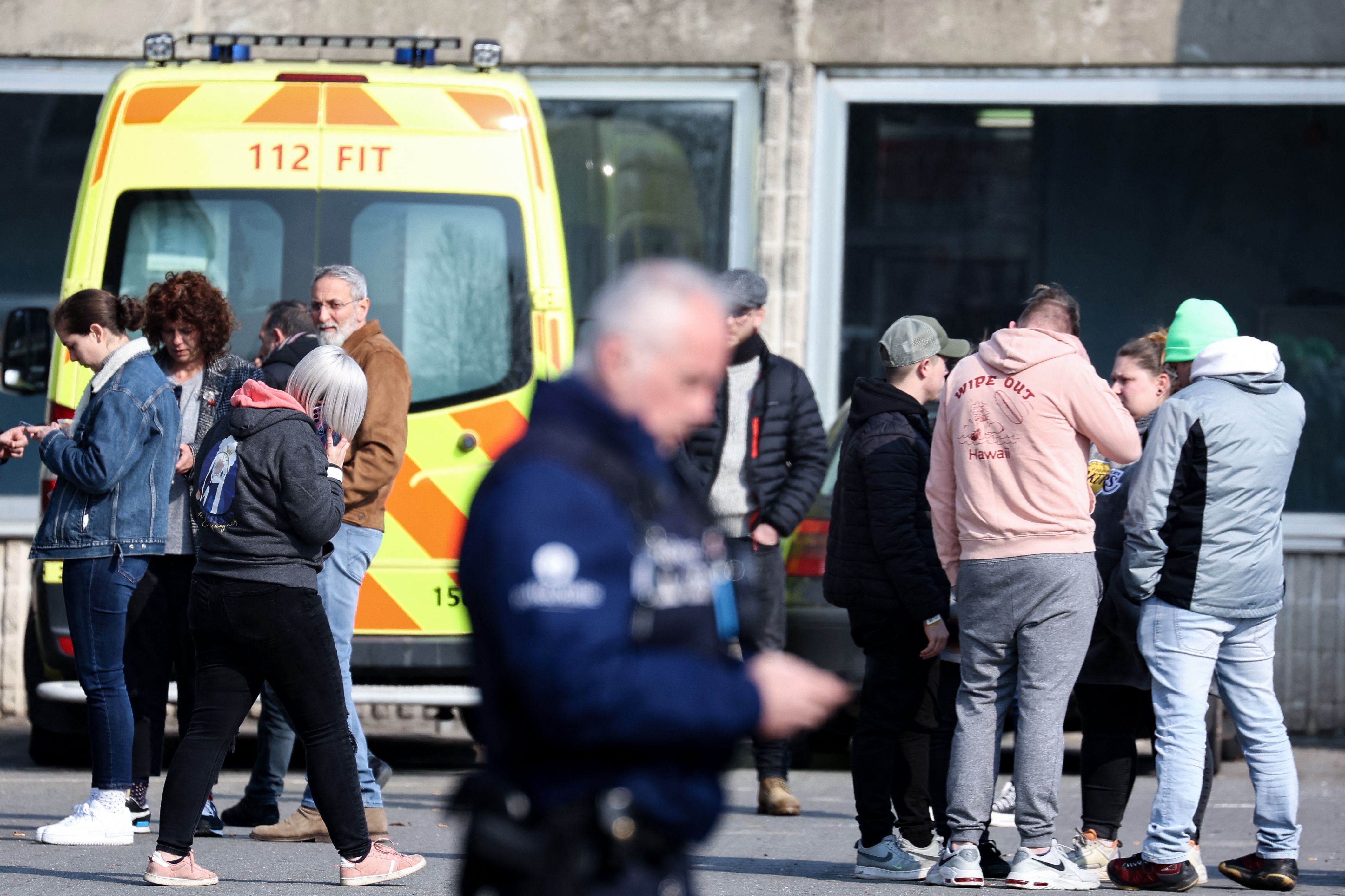 Witnesses and relatives of victims outside a sports hall that was turned into an emergency centre for medical and police support