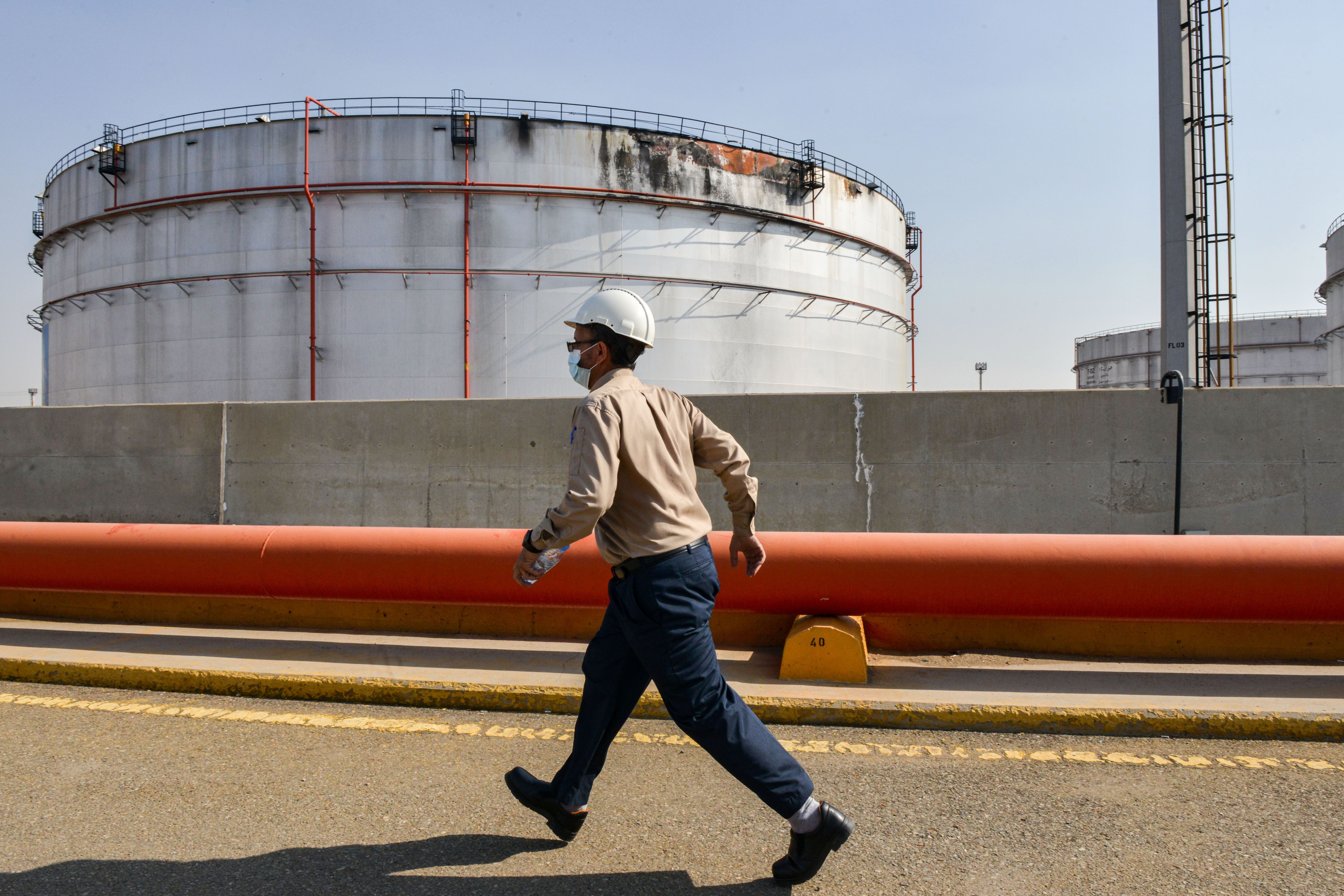 File photo: An employee at the Saudi Aramco oil facility walks near a damaged silo, at the plant in Saudi Arabia’s Red Sea city of Jeddah, 24 November 2020