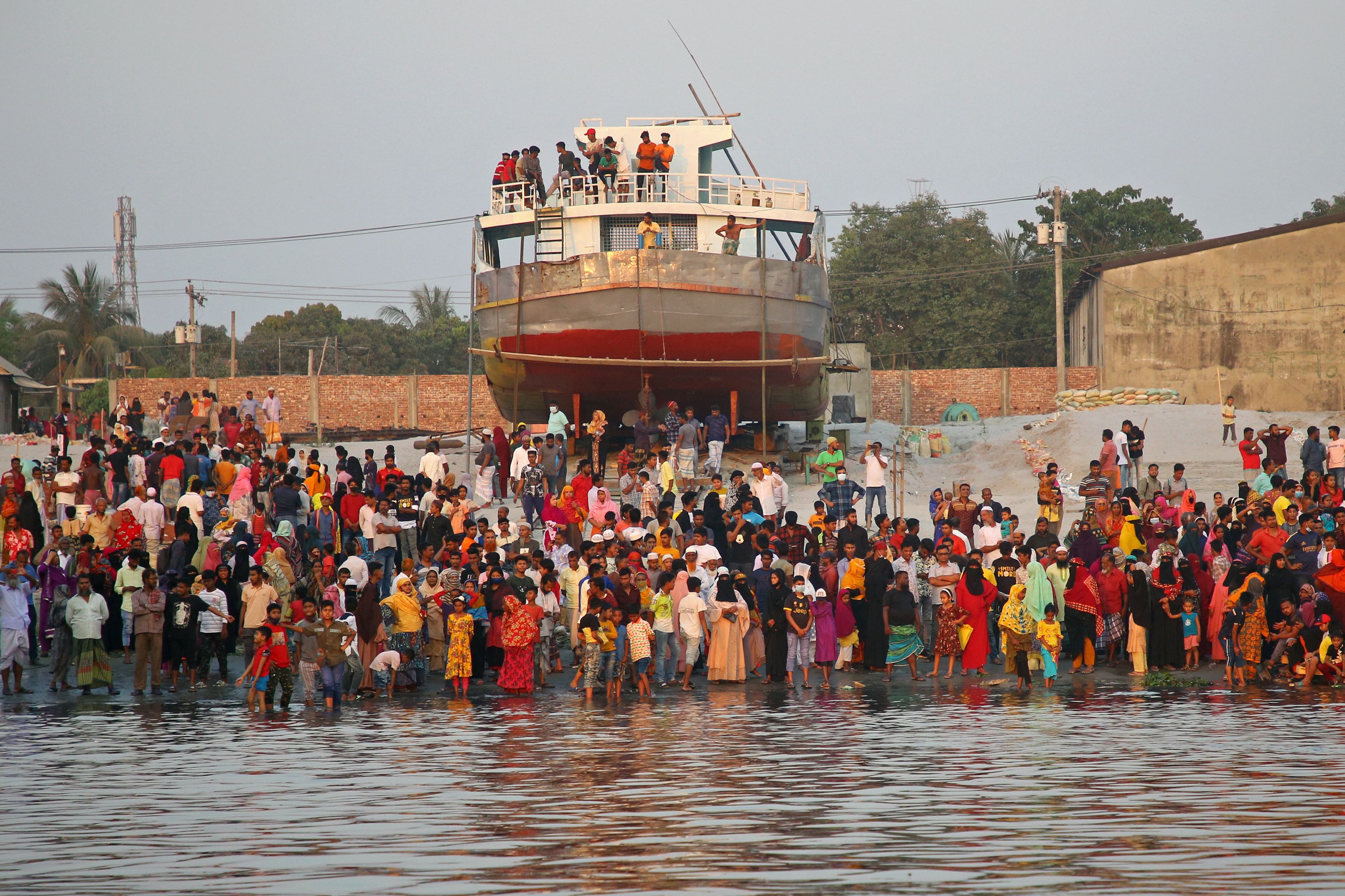 Onlookers and relatives of the missing people stand at the site of an accident after a ferry sank in Shitalakshya river in Narayanganj. Bangladesh, 20 March 2022