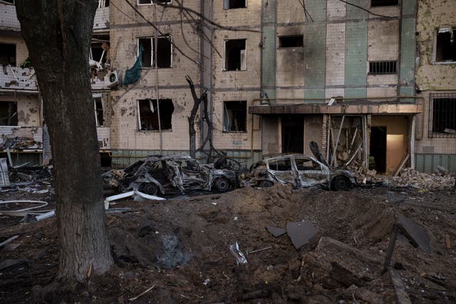A crater is seen in front of a heavily damaged residential building in Kyiv (Felipe Dana/AP)