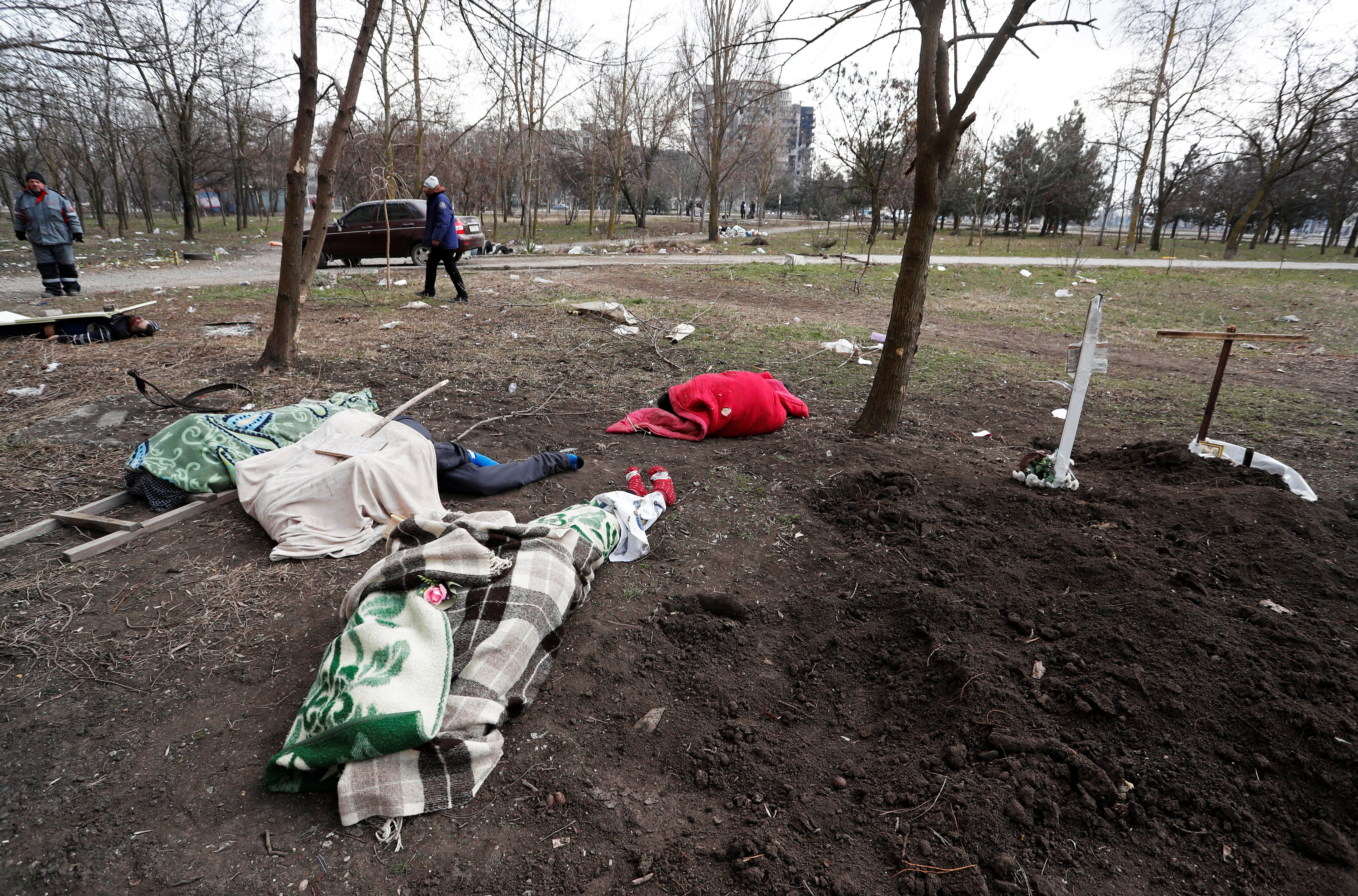 Bodies of people killed during Ukraine-Russia conflict lie on the ground beside the graves of local residents buried in the residential area in the besieged southern port city of Mariupol, Ukraine