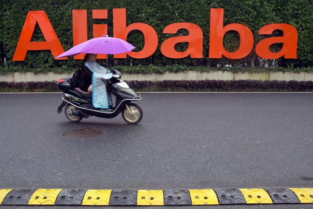 <p>FILE - A woman rides a scooter past the company logo outside the Alibaba Group headquarters in Hangzhou, China </p>