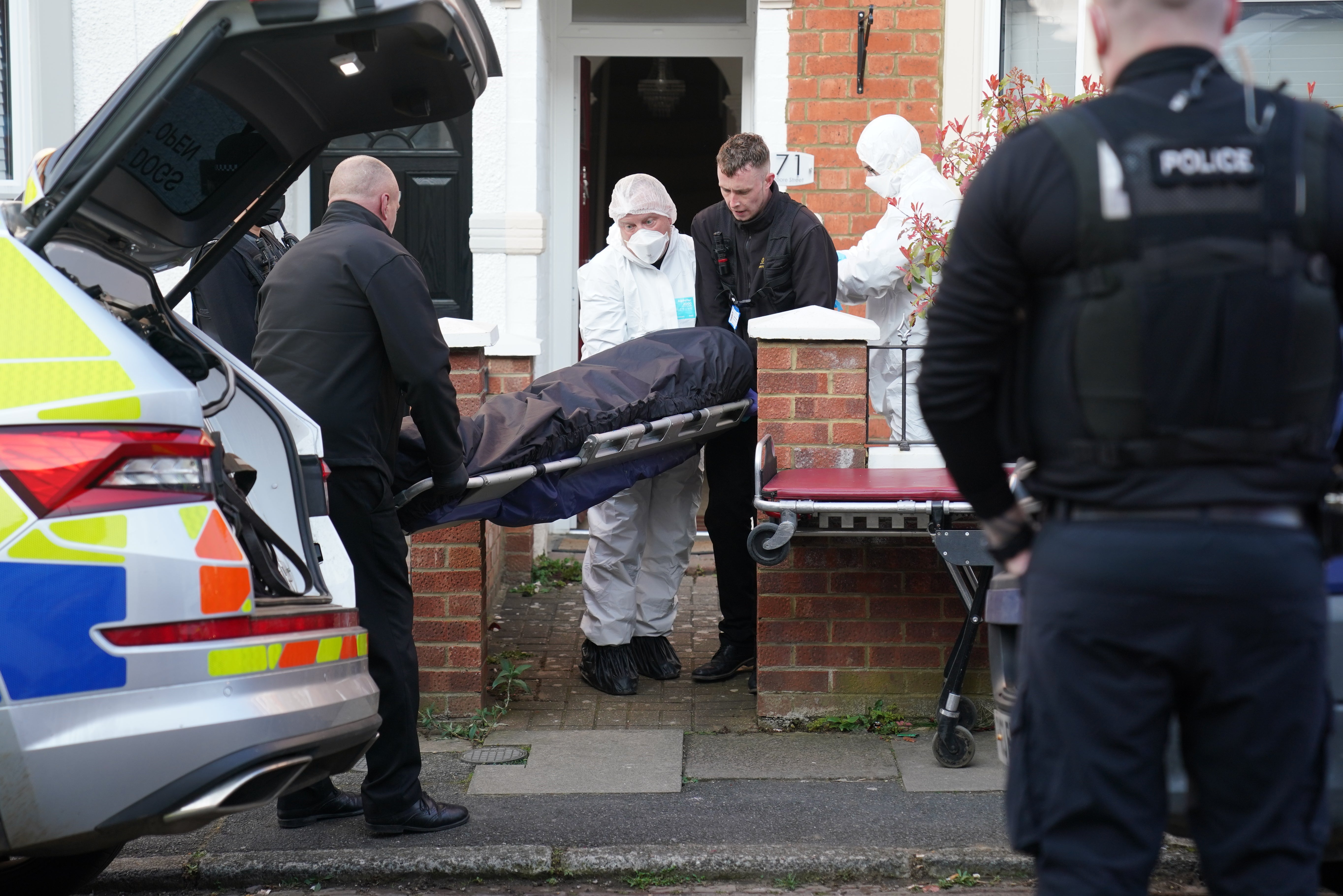 The body is removed from the property in Moore Street, Kingsley, Northampton following its discovery in the rear garden (PA)