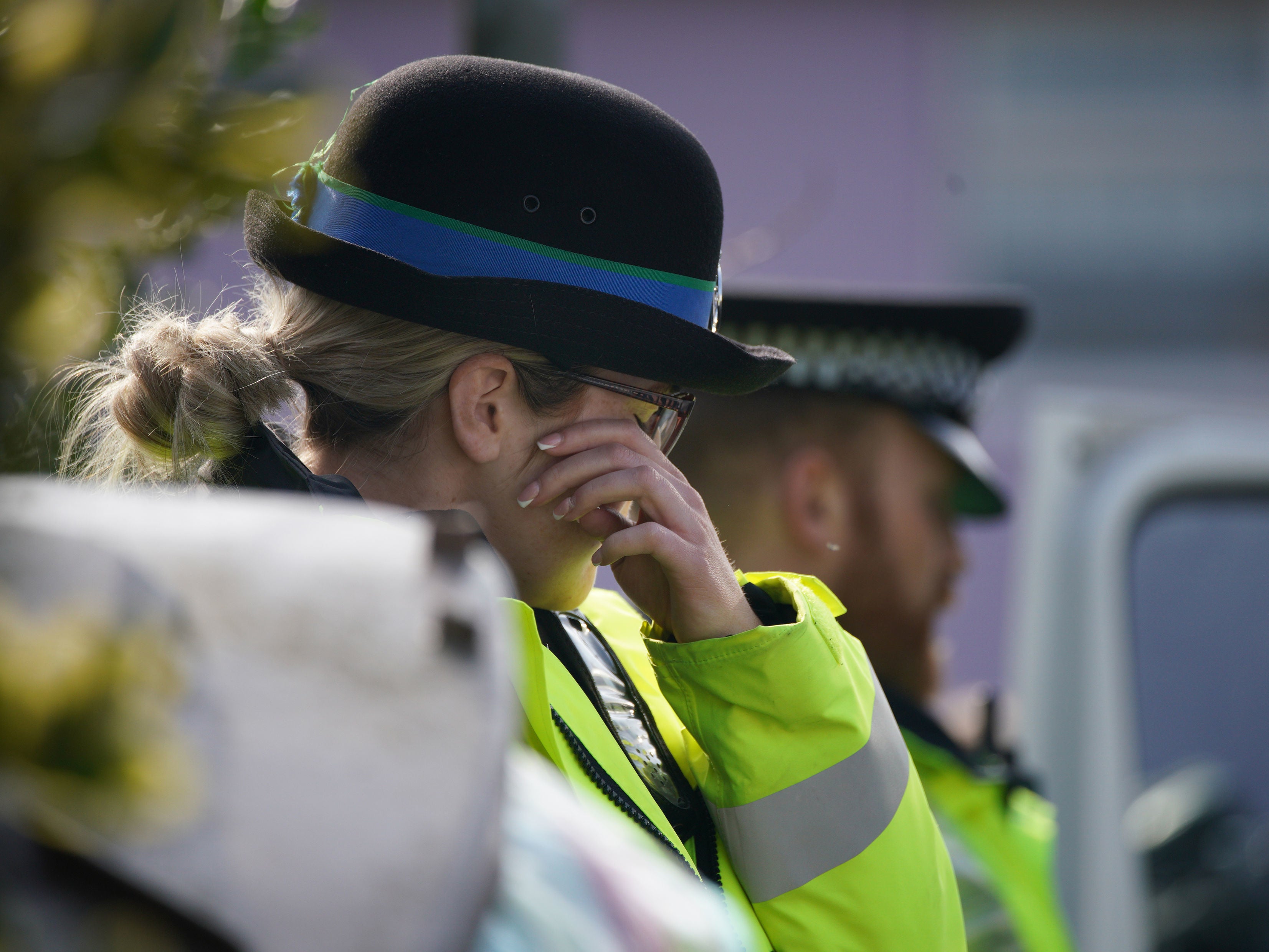 A police officer wipes her eyes outside the house in St Helens
