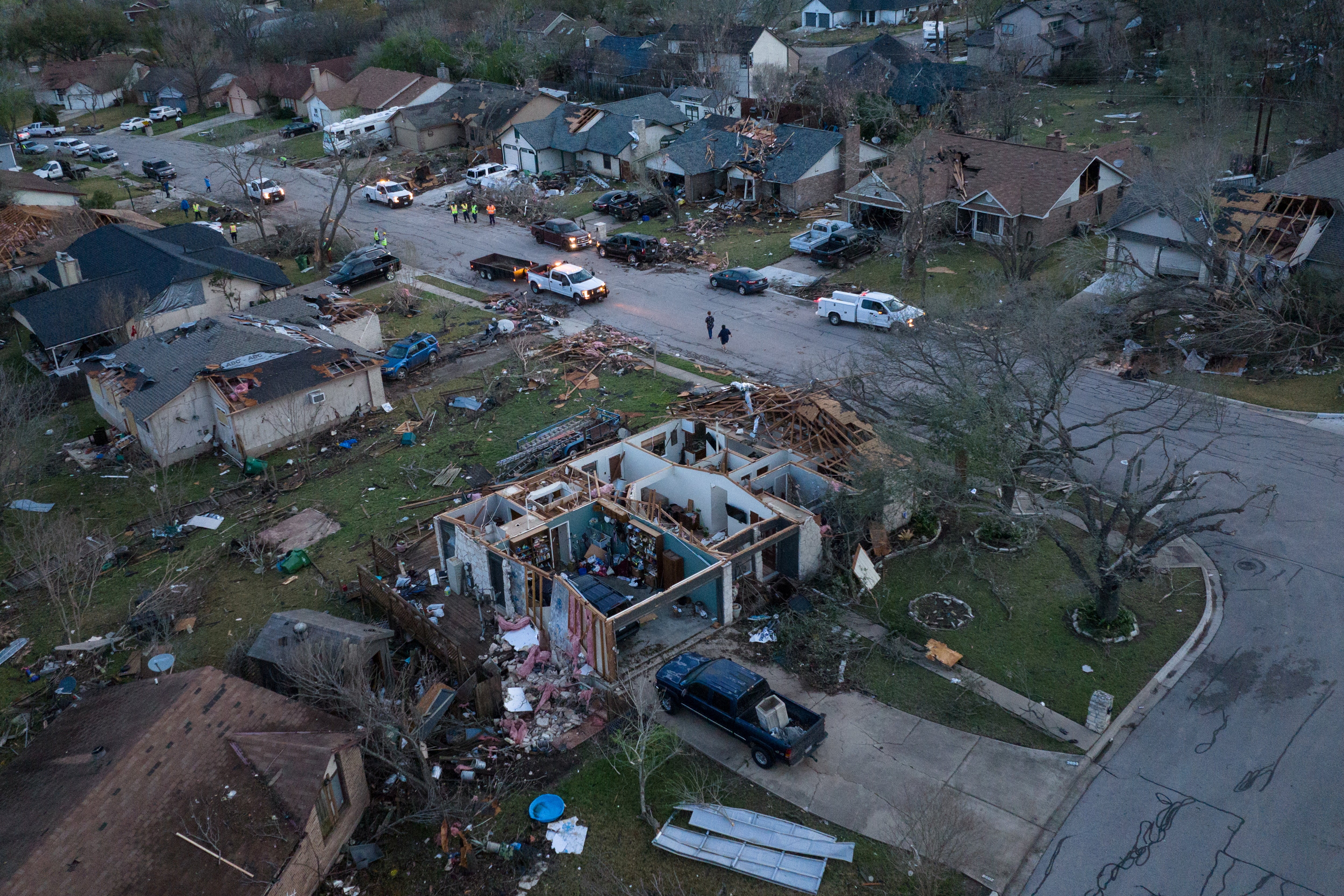 A search and rescue team is seen as residents walk past destroyed homes in the aftermath of a tornado in Round Rock on Tuesday