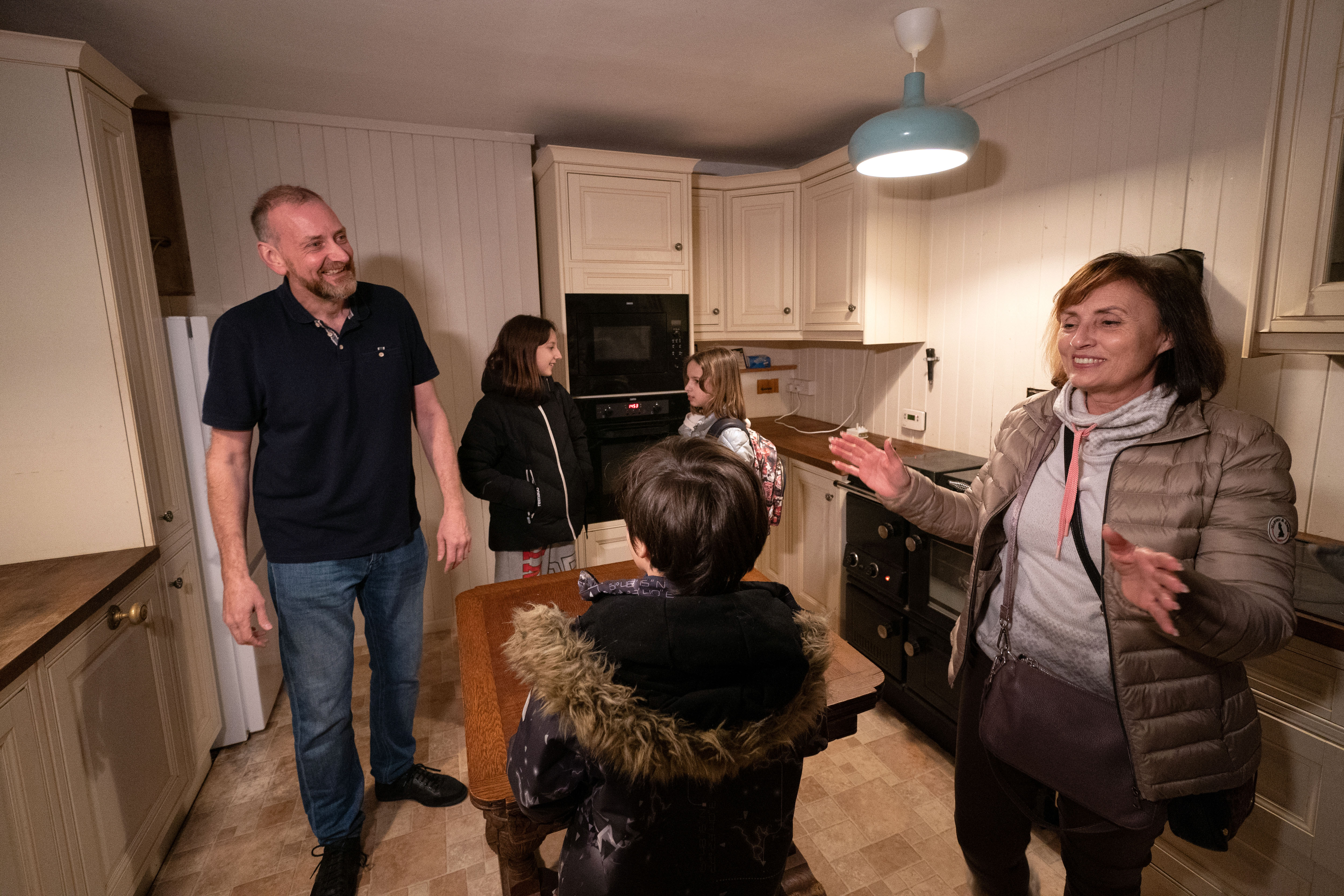 Businessman Mick Swinhoe shows Iryna Starkova and her grandchildren around the kitchen of their new home in Caldecote near Cambridge
