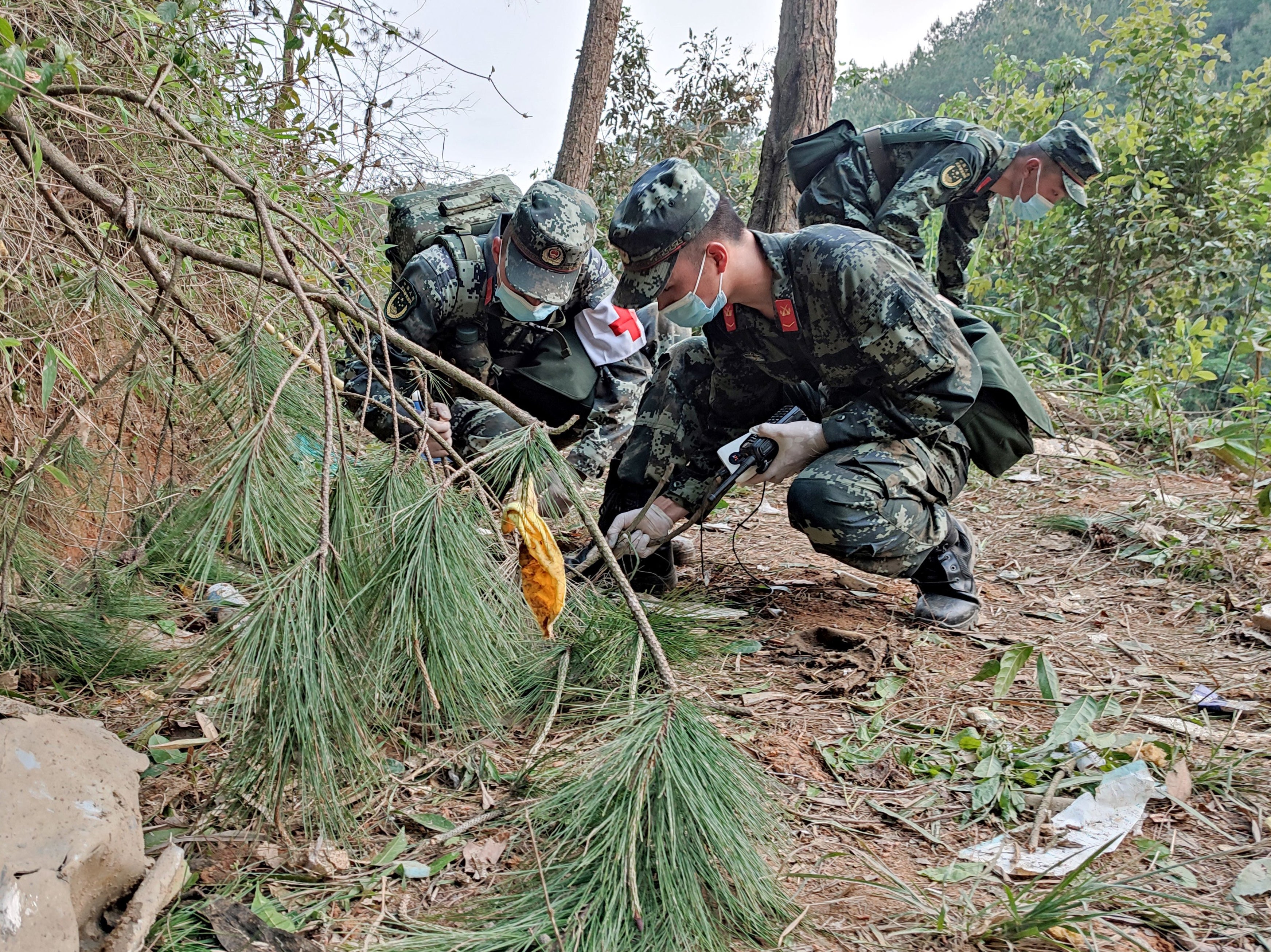 <p>This photo taken on 21 March 2022 shows paramilitary police officers conducting a search at the site of the China Eastern Airlines plane crash in Tengxian county, Wuzhou city, in China’s southern Guangxi region</p>