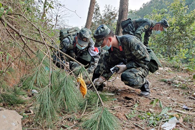 <p>This photo taken on 21 March 2022 shows paramilitary police officers conducting a search at the site of the China Eastern Airlines plane crash in Tengxian county, Wuzhou city, in China’s southern Guangxi region</p>