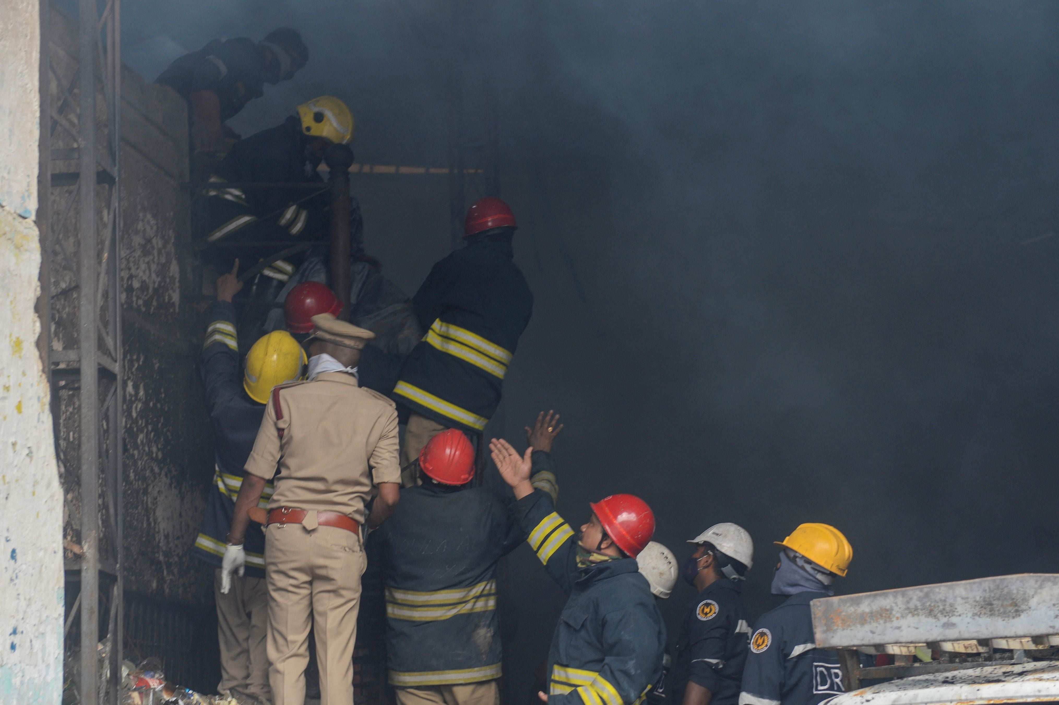 Firefighters and rescue workers recover a body from a warehouse after a fire broke out in Secunderabad