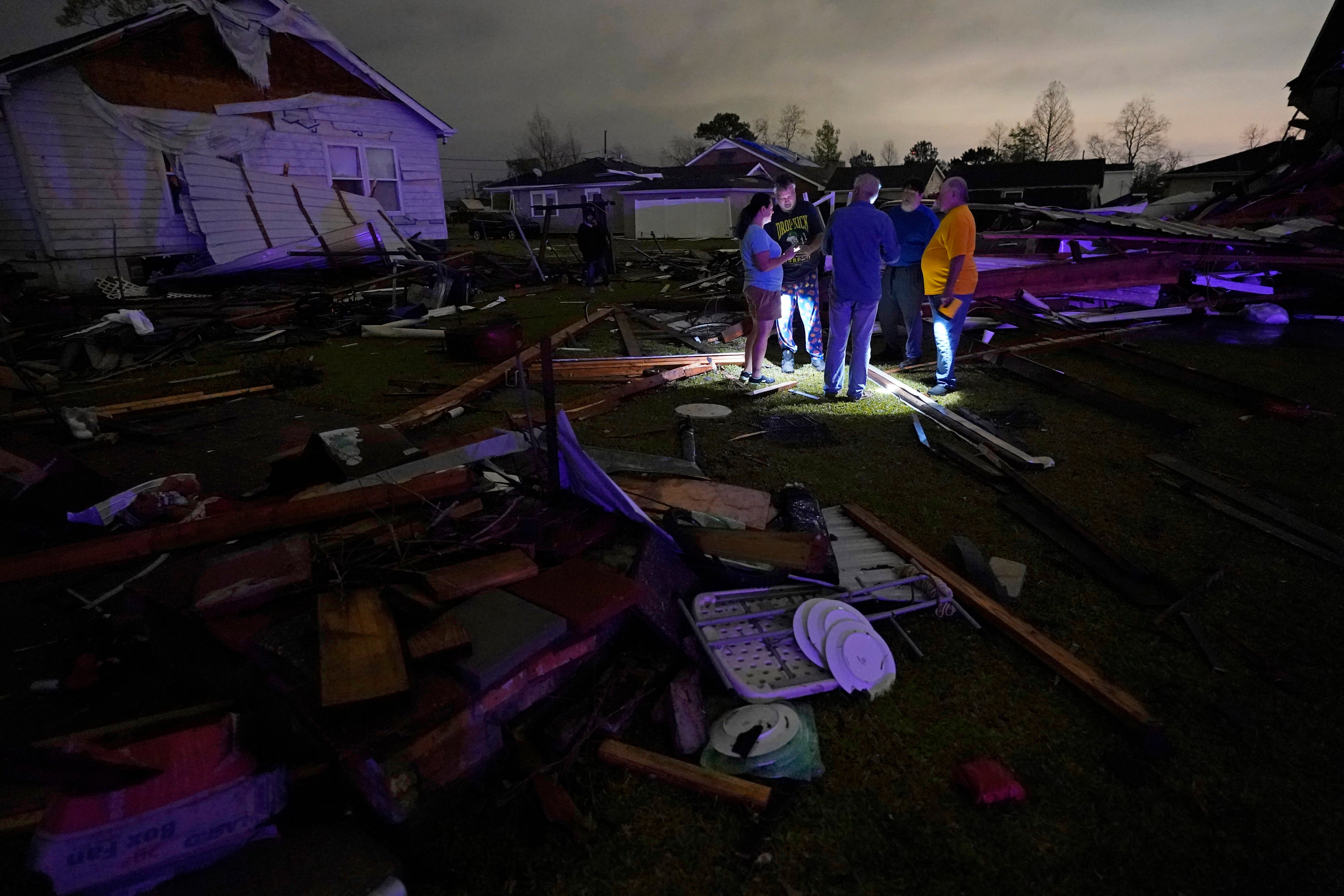 Christine Wiecek, left, and her husband Robert Patchus, second left, talk to neighbors among debris of their damaged homes after a tornado struck in Arabi, Louisiana on Tuesday