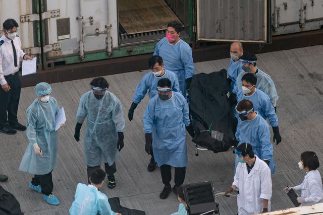 <p>Workers transfer the body of a deceased person at a mortuary in Hong Kong, 7 March 2022</p>