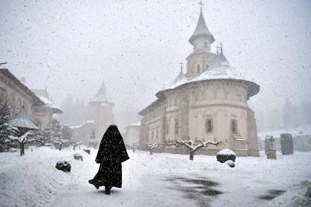 <p>Romanian Orthodox monk Father Mikhail departs after mass at the church in Putna monastery, Romania</p>