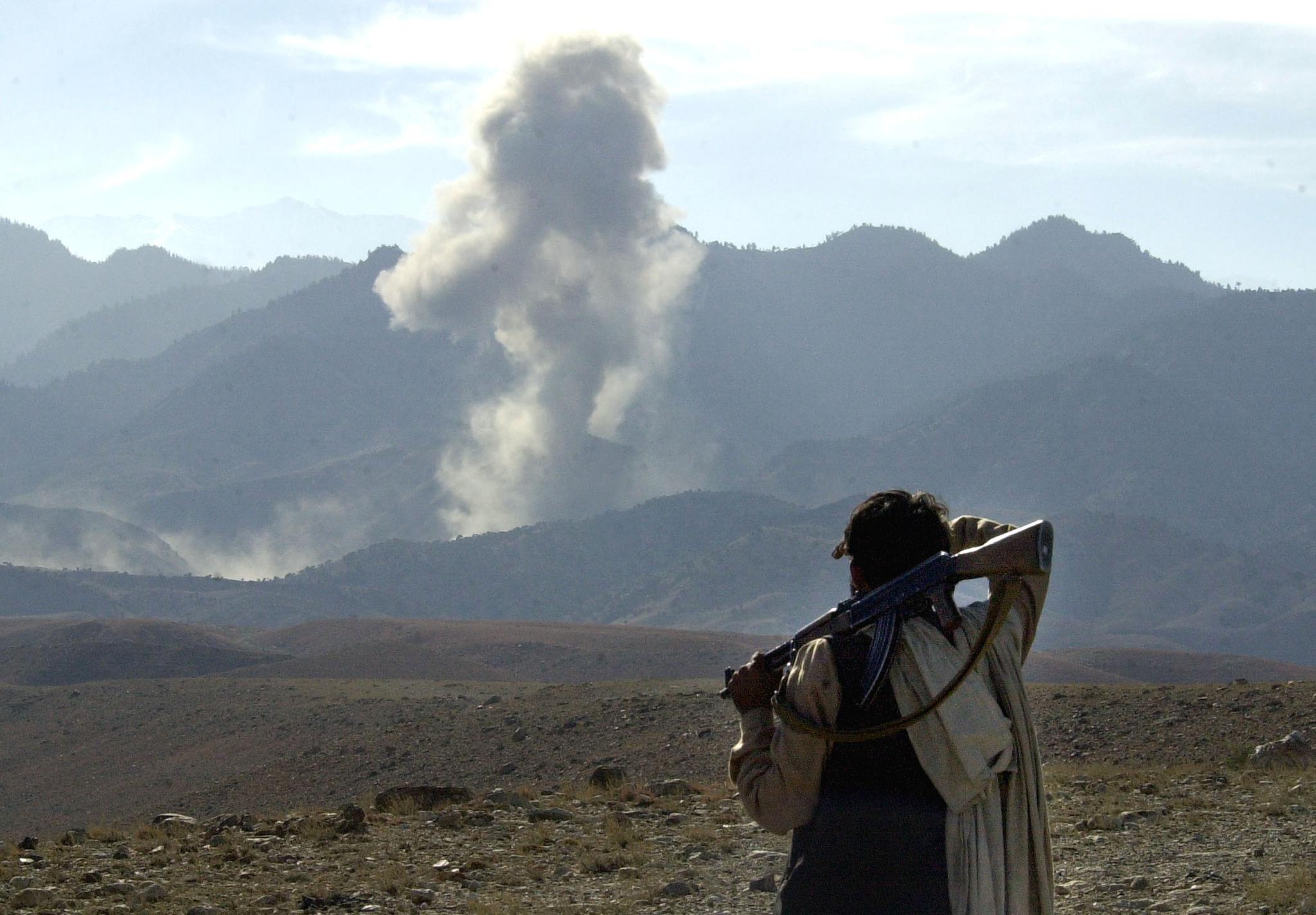 Afghan fighters watch a bomb explode about 2km away after an attack by US warplanes on the al-Qaeda position in the Tora Bora mountains, 5 December 2001