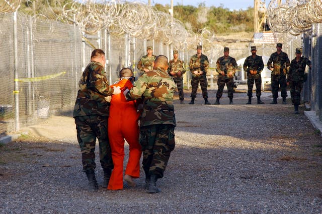 <p>US army military police escort a detainee to his cell in Camp X-Ray at the Guantanamo Bay naval base in Cuba</p>