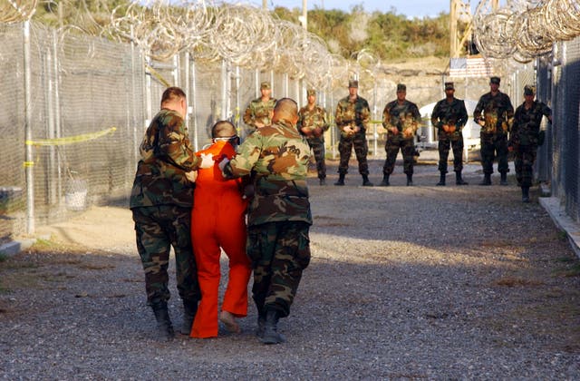 <p>US army military police escort a detainee to his cell in Camp X-Ray at the Guantanamo Bay naval base in Cuba</p>