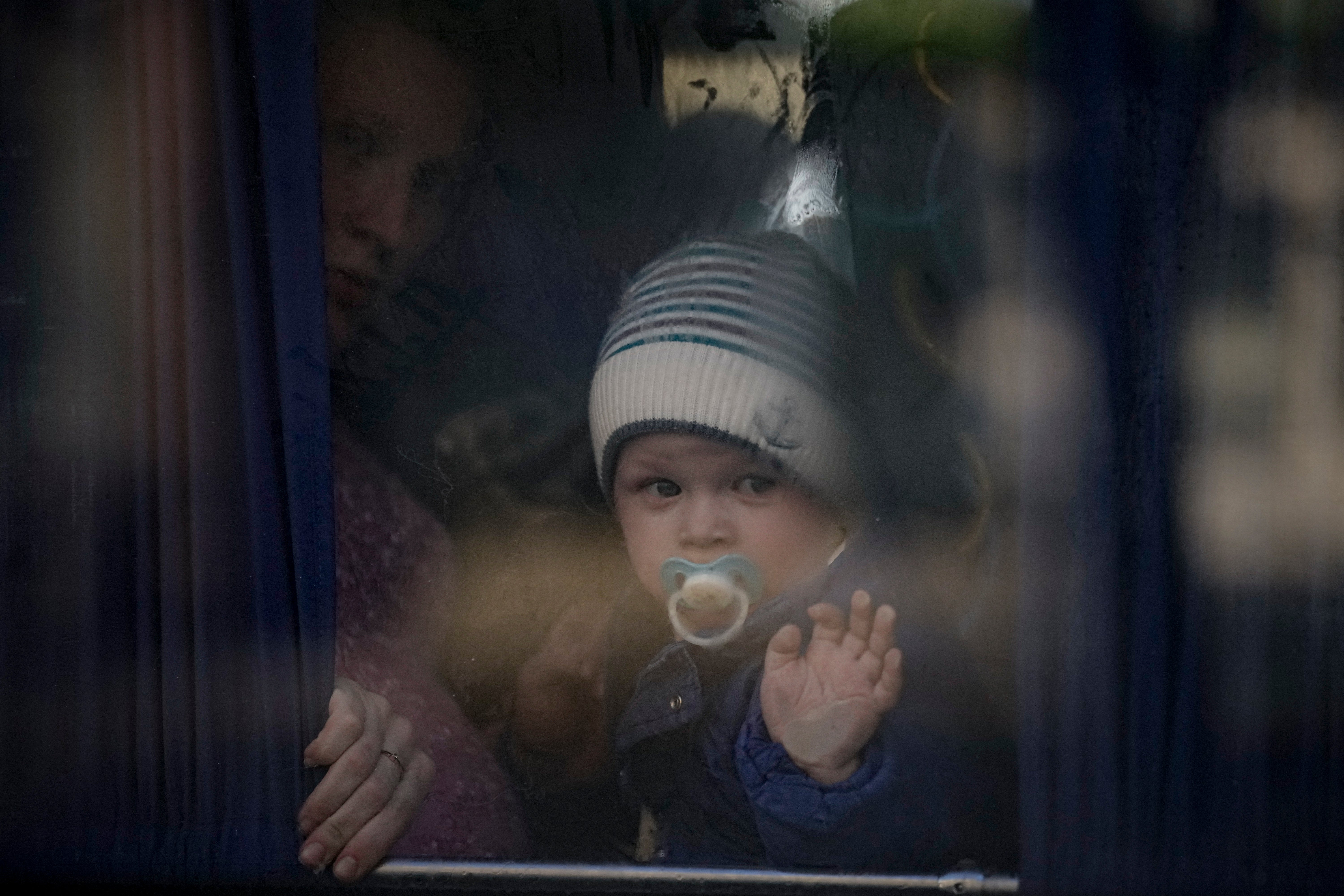 A refugee holds a baby while waiting on a bus for Ukrainian police to check papers and belongings in Brovary (Vadim Ghirda/AP)