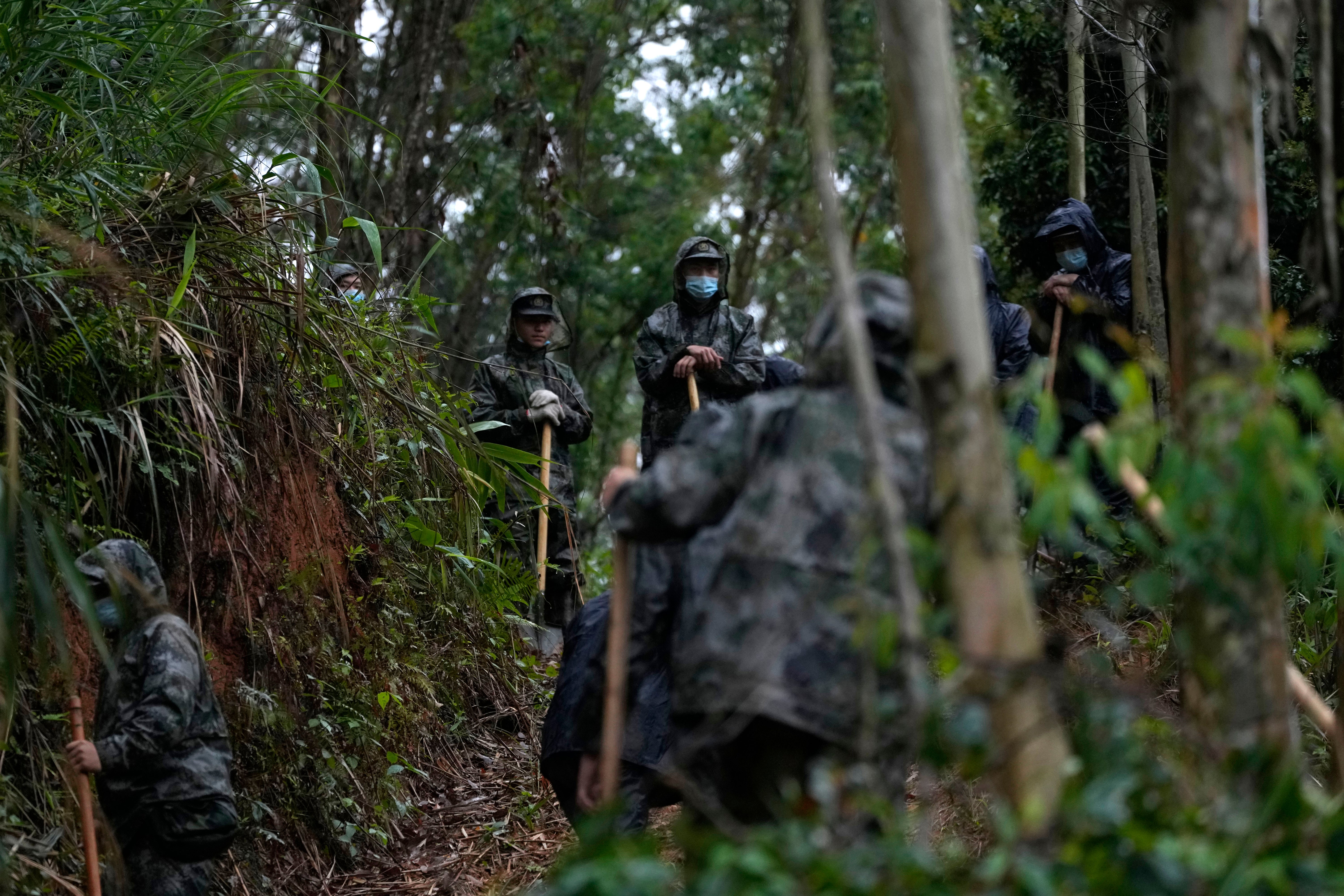 <p>Search and rescue workers pause along a trail near the China Eastern crash site on 24 March in Molang village, in southwestern China's Guangxi province</p>