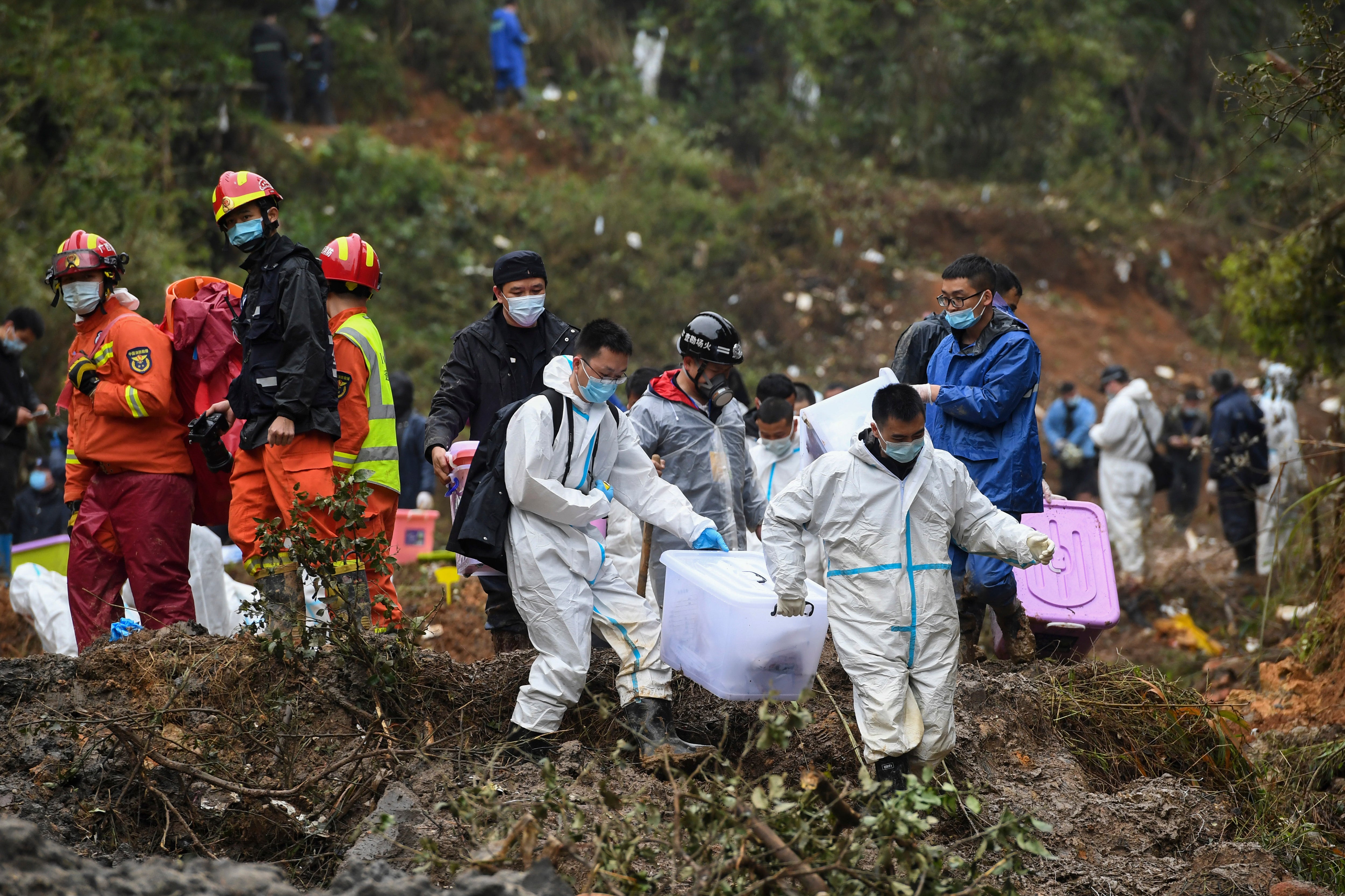 Search and rescue workers carry boxes which were believed to contain victim’s belonging at the China Eastern flight crash site