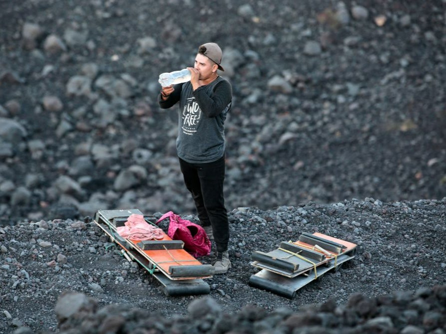 Tour guides carry tourist’s boards up the volcano