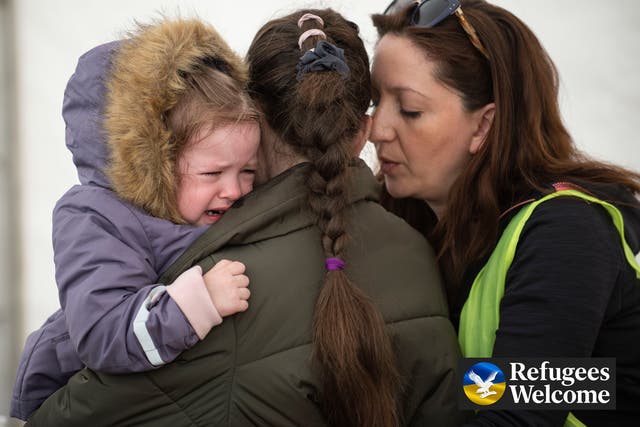 <p>A Ukrainian mother holds her daughter as they weep at Záhony train station on the Hungarian/Ukrainian border as a volunteer attempts to console them</p>
