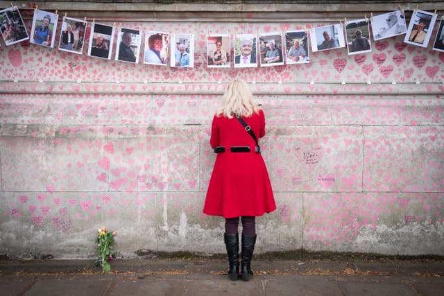 A family member pays their respects to those who lost their lives to Covid -9 as they mark the one-year anniversary of National Covid Memorial Wall, London (Stefan Rousseau/PA)