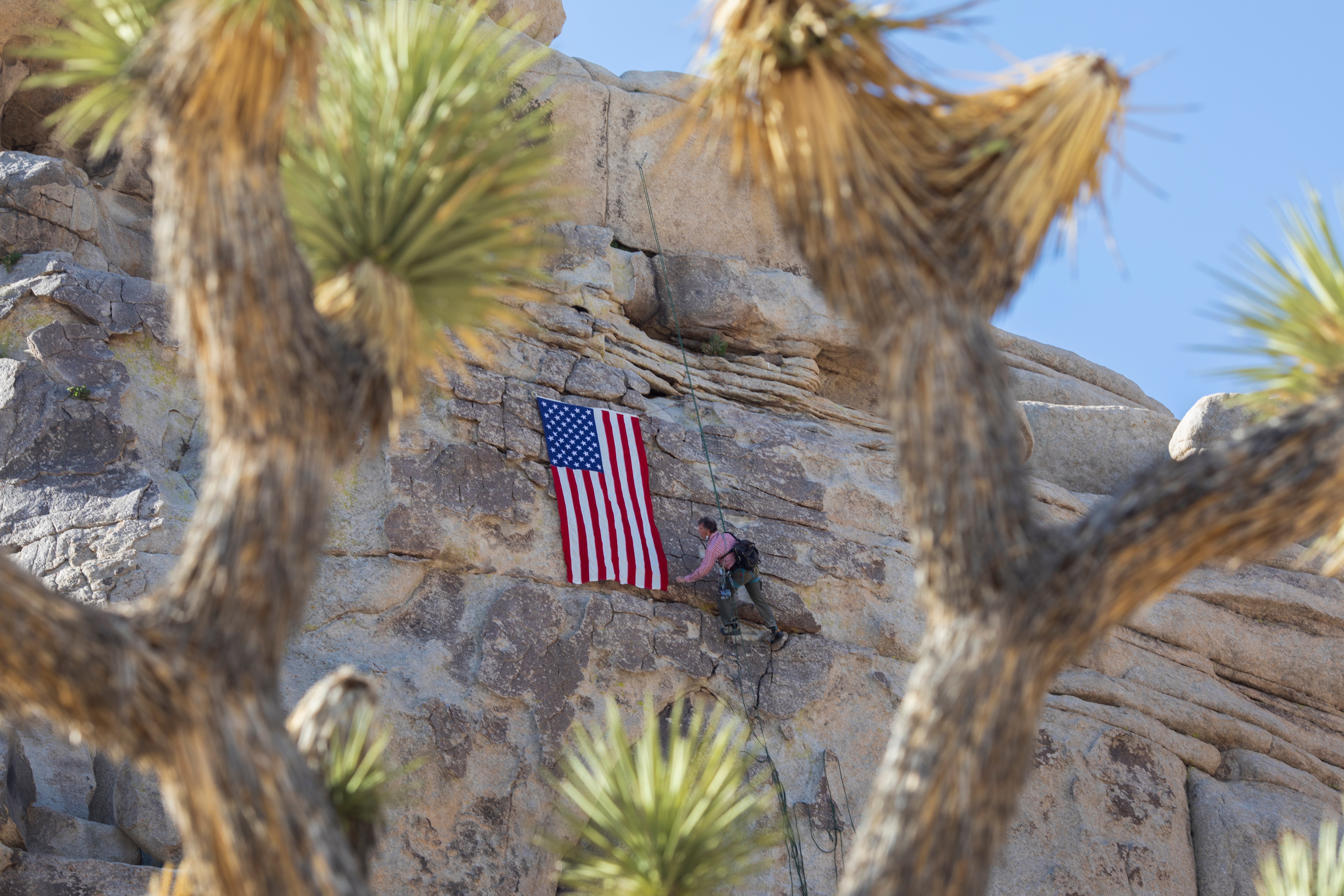 File photo: A climbing guide hangs an American flag from a crag at Joshua Tree National Park