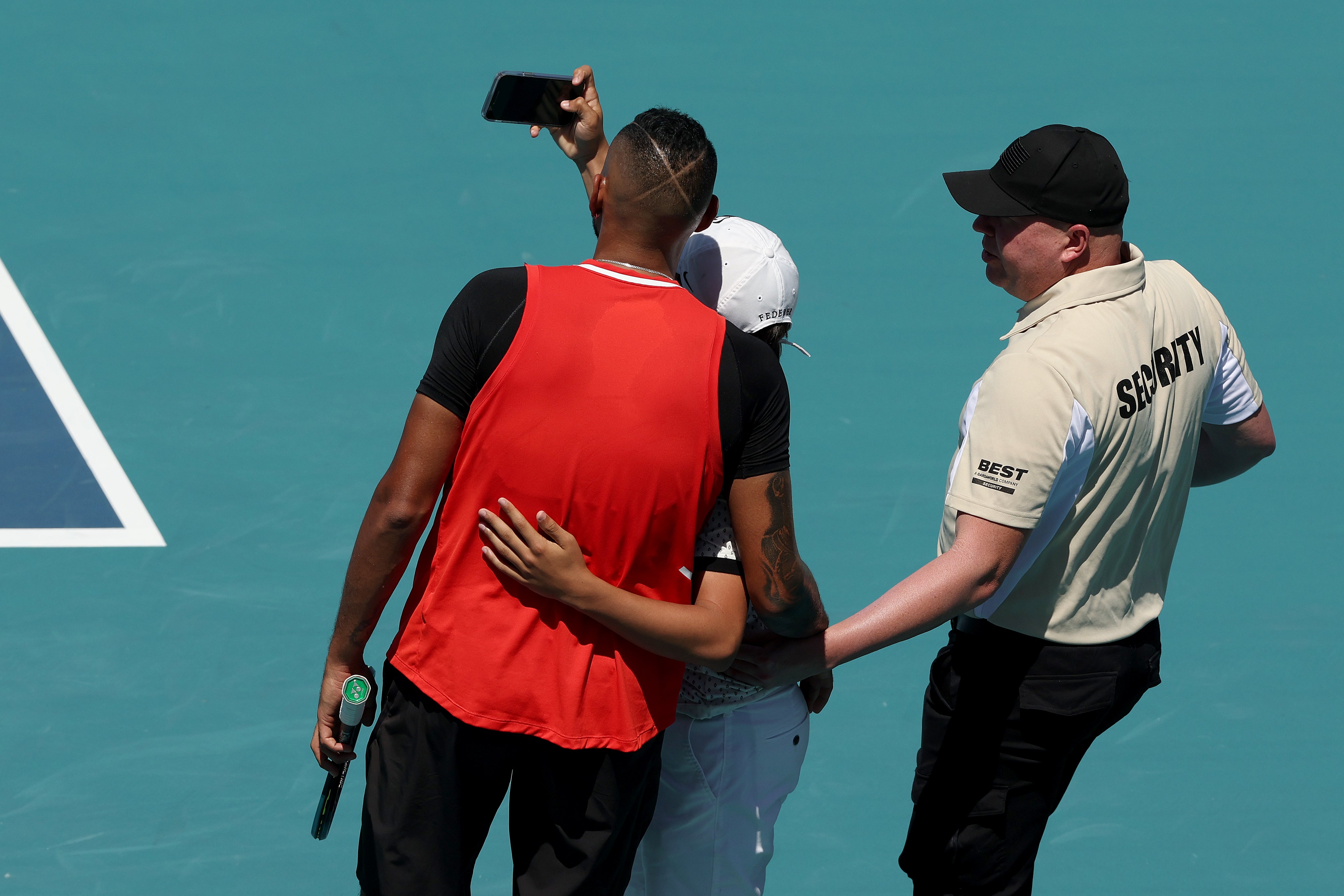 Nick Kyrgios poses for a selfie with an intruding spectator