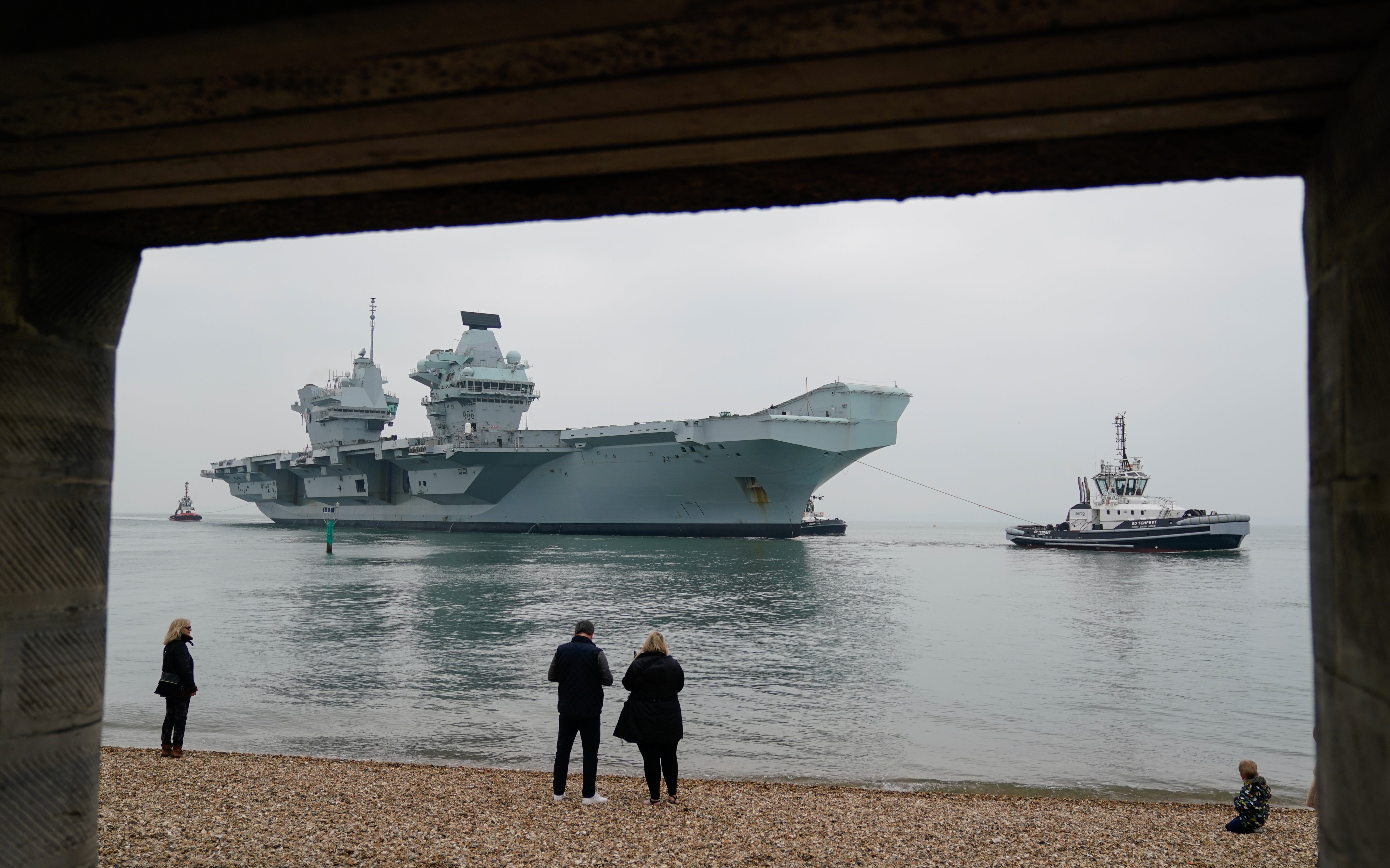 People look on as the Royal Navy aircraft carrier HMS Queen Elizabeth arrives back in Portsmouth (Andrew Matthews/PA)
