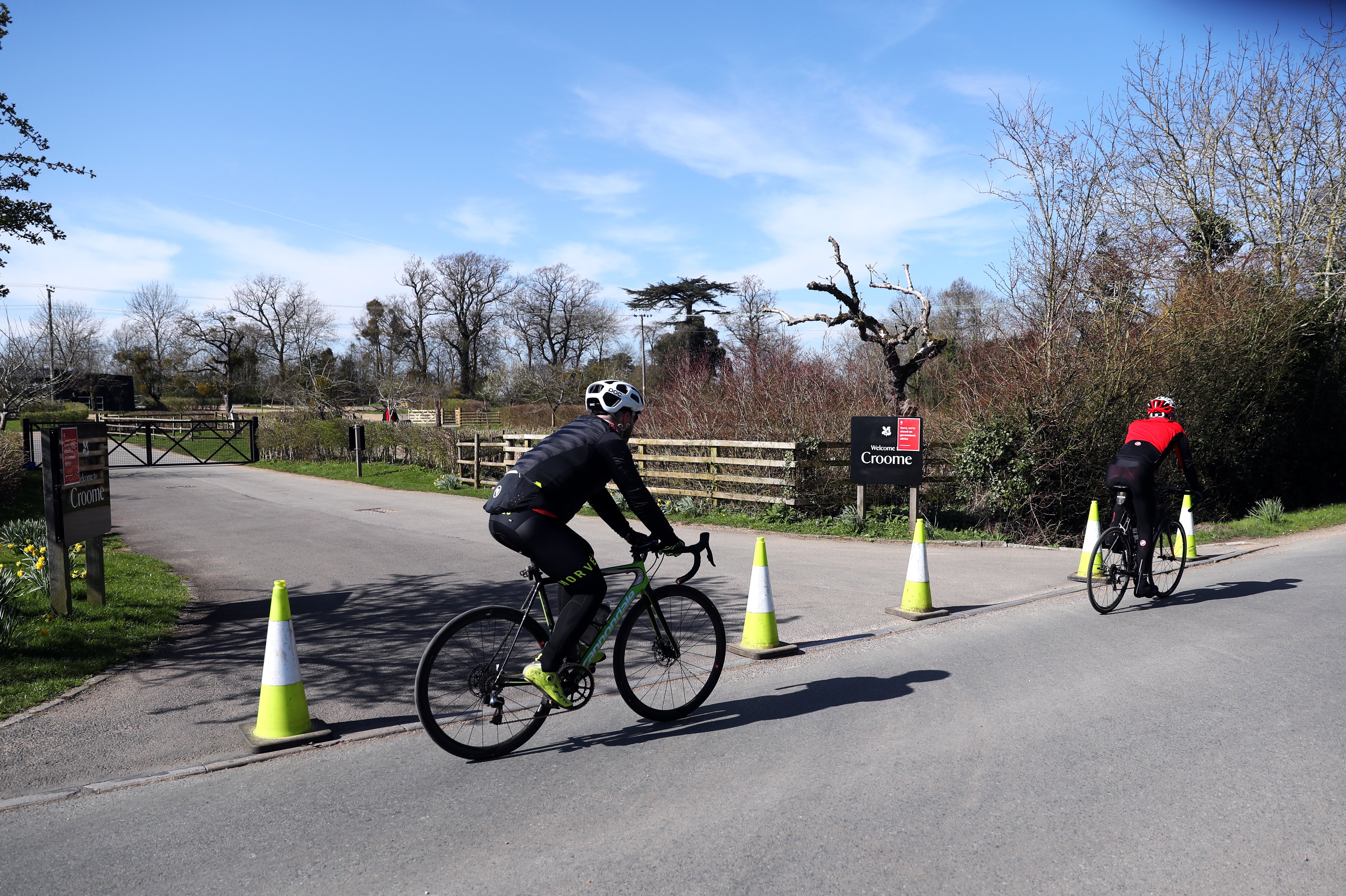 Cyclists pass the blocked entrance to Croome in Worcestershire after the National Trust announced it has shut down all of its parks and and gardens during the pandemic