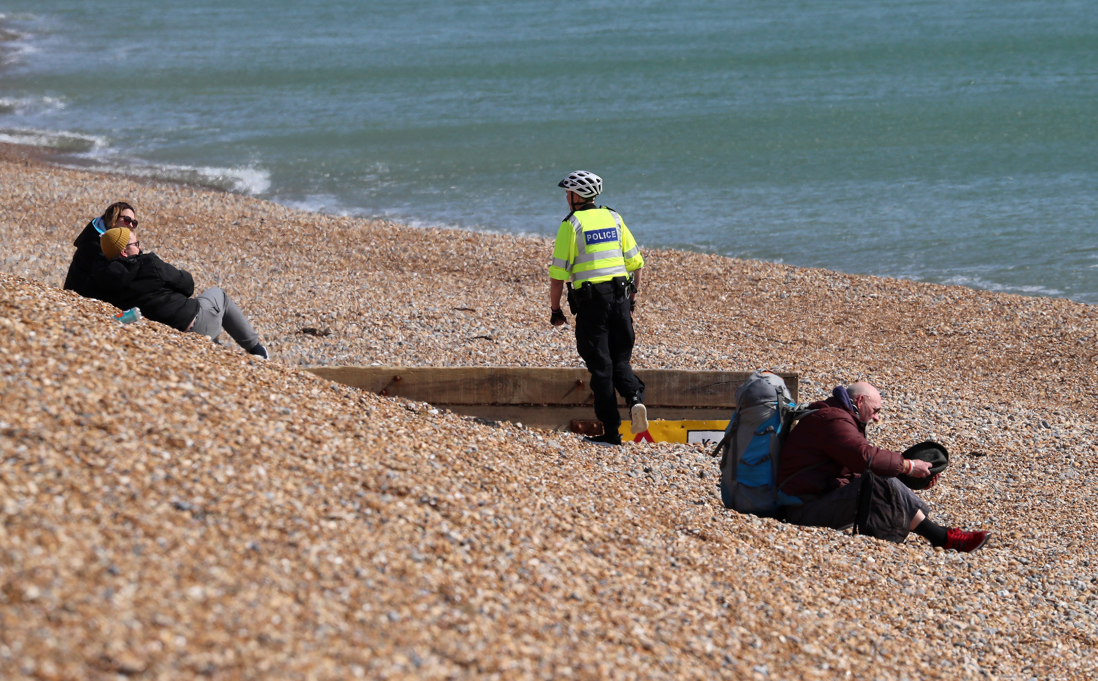 A police officer asks people to leave the beach in Brighton during lockdown