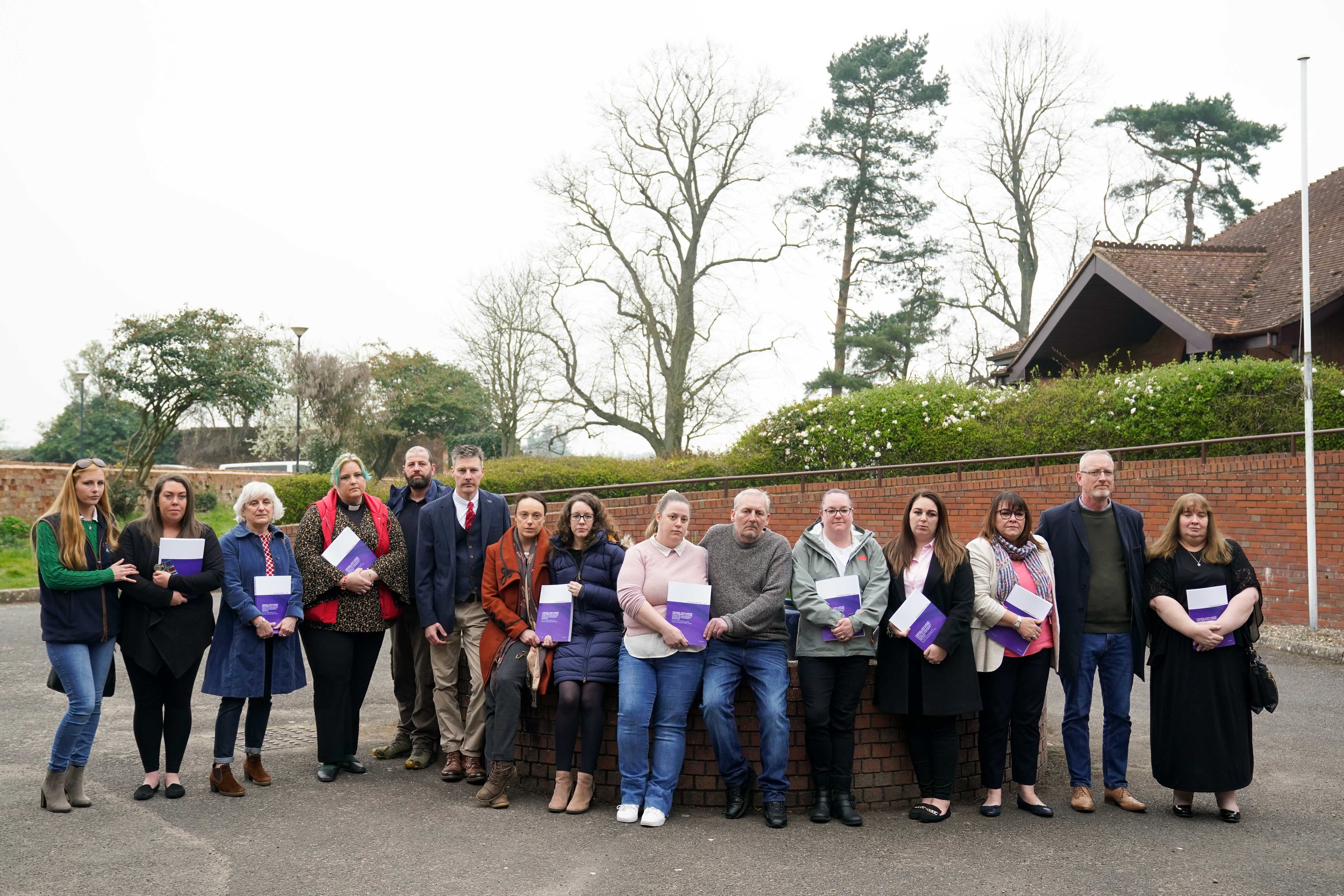 (L to R) Chelsey Campbell, Carley McKee, Fiona Carr, Charlotte Cheshire, Colin Griffiths, Richard Stanton, Rhiannon Davies, Kayleigh Griffiths, Nicky Lauder, David Boylett, Hayley Matthews, Steph Hotchkiss, Julie Rowlings, Neil Rowlings and Sonia Leigh stand with the final Ockenden report (Jacob King/PA)