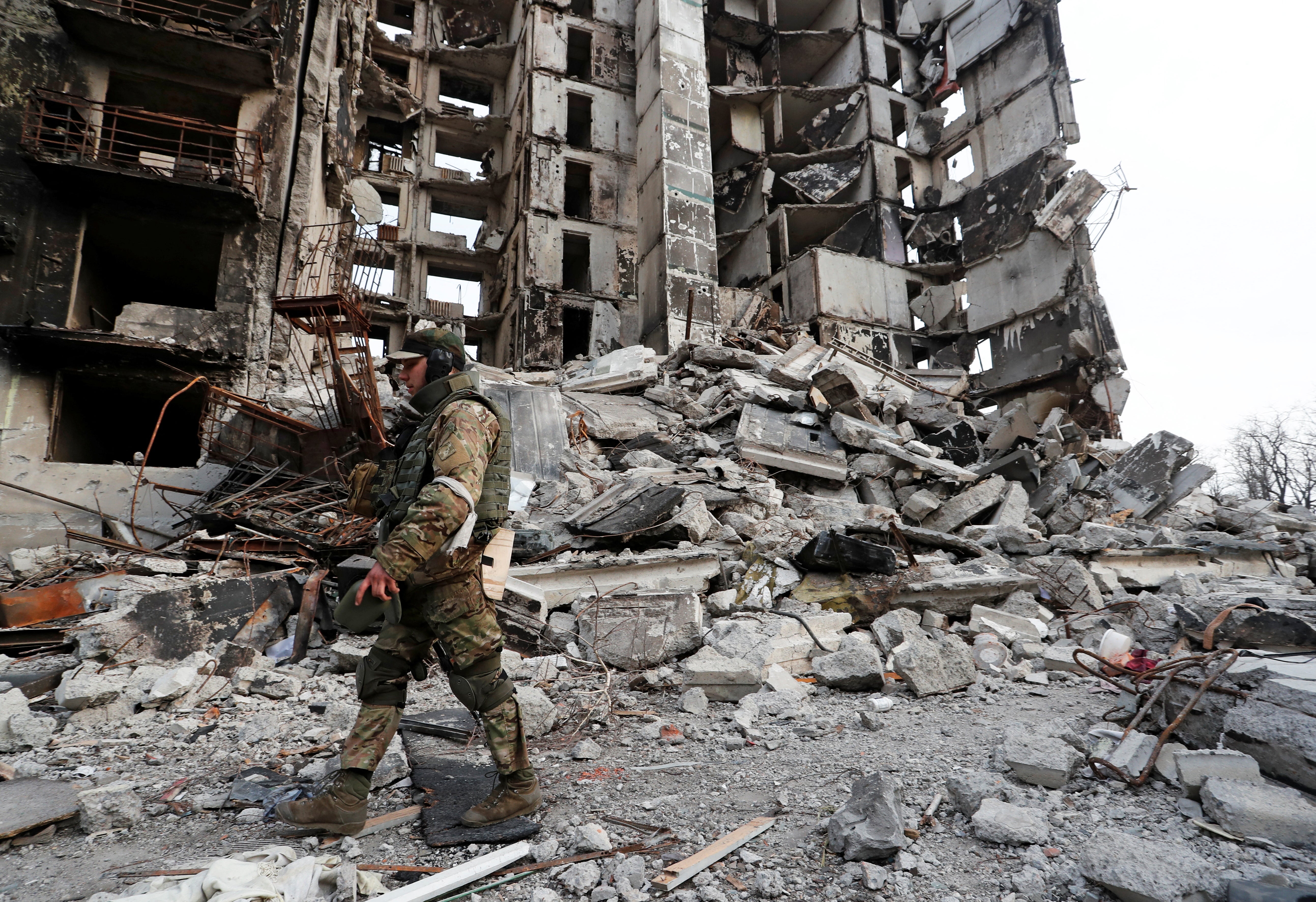A service member of pro-Russian troops walks on the ruins of an apartment building destroyed during Ukraine-Russia conflict in the besieged southern port city of Mariupol