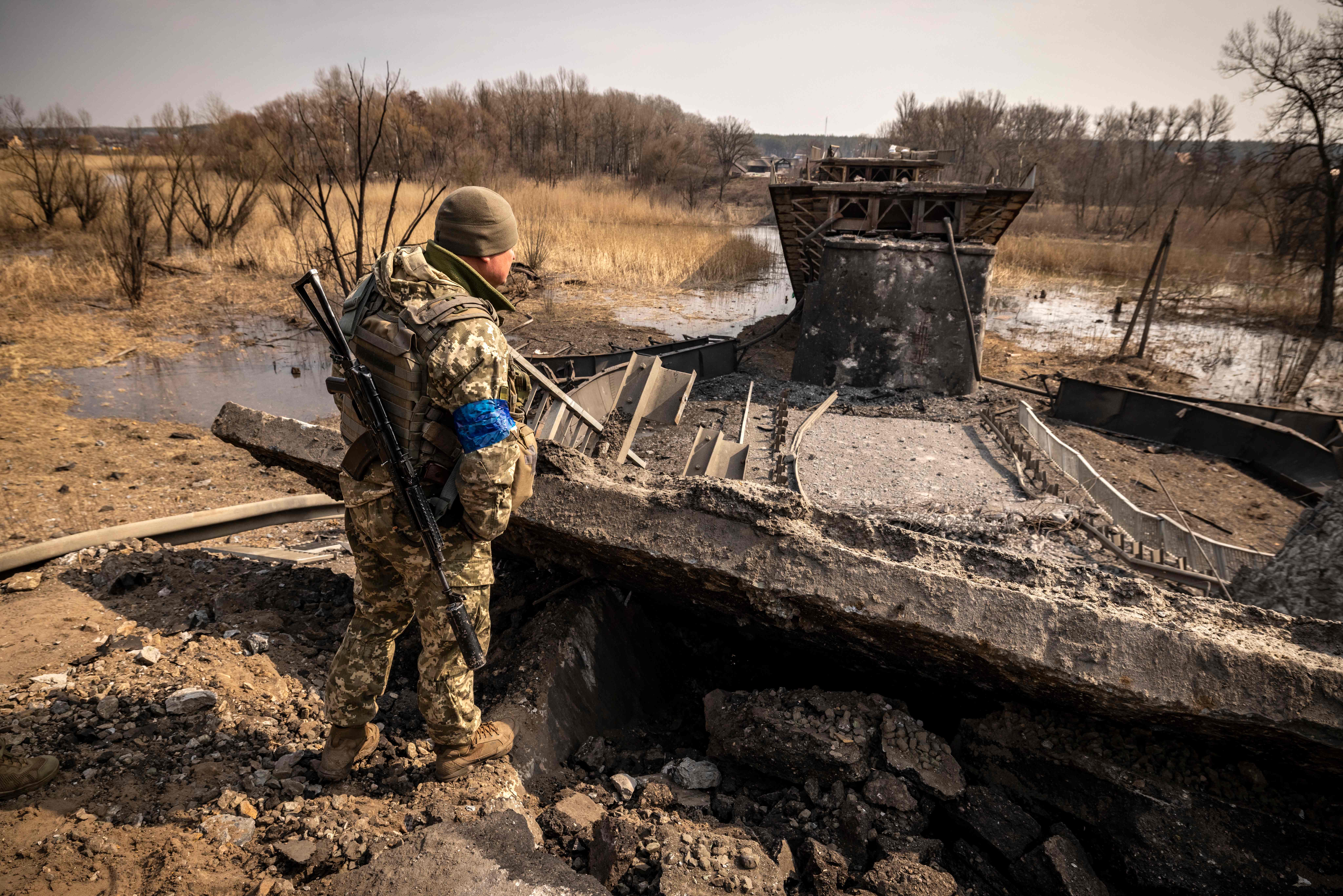 A Ukrainian soldier patrols near a bridge destroyed by the Russian army in the town of Rogan, east of Kharkiv, 30 March 2022