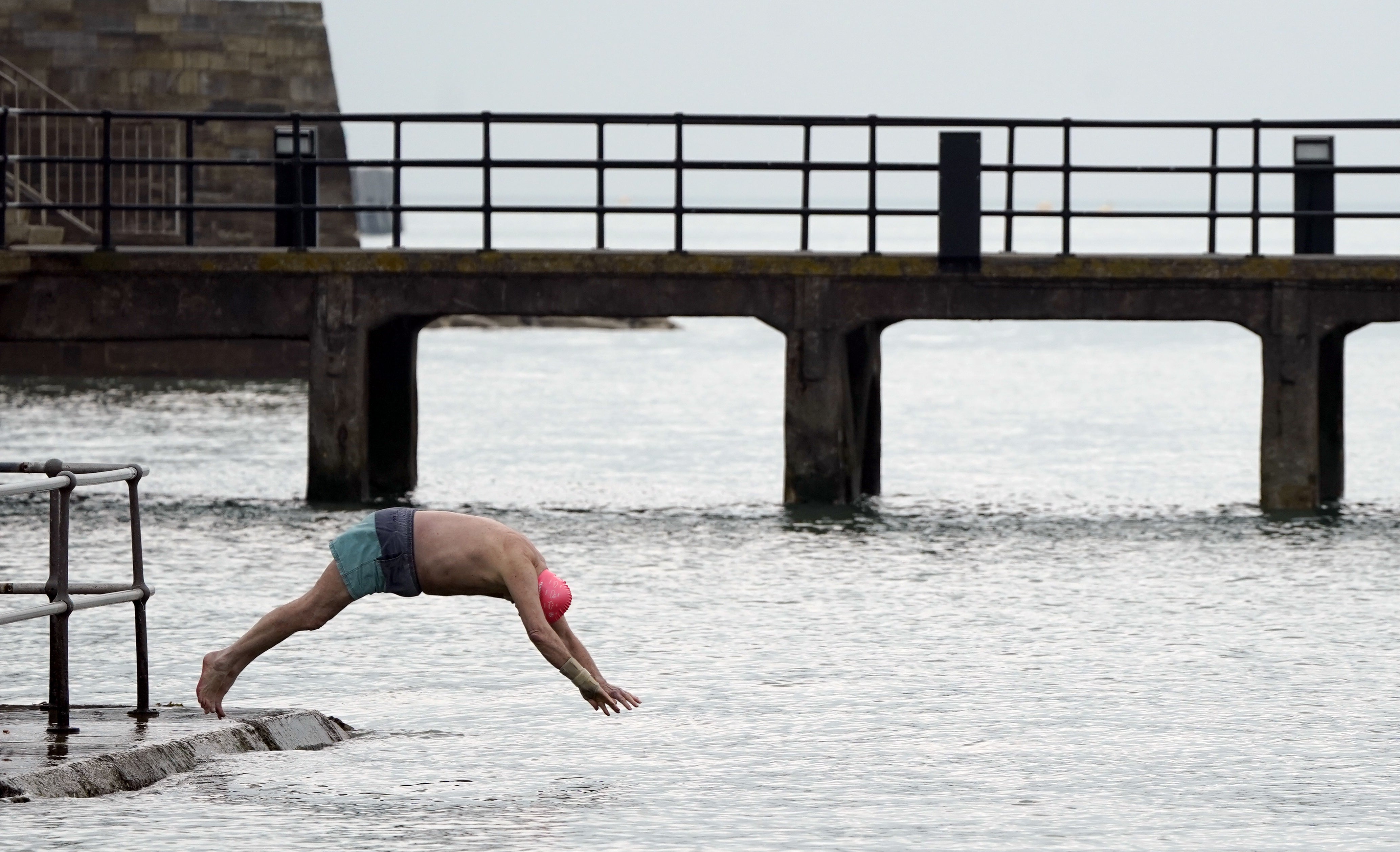 A person presumably less concerned with the plunging temperatures dives into the sea next to the Hot Walls in Old Portsmouth (Andrew Matthews/PA)
