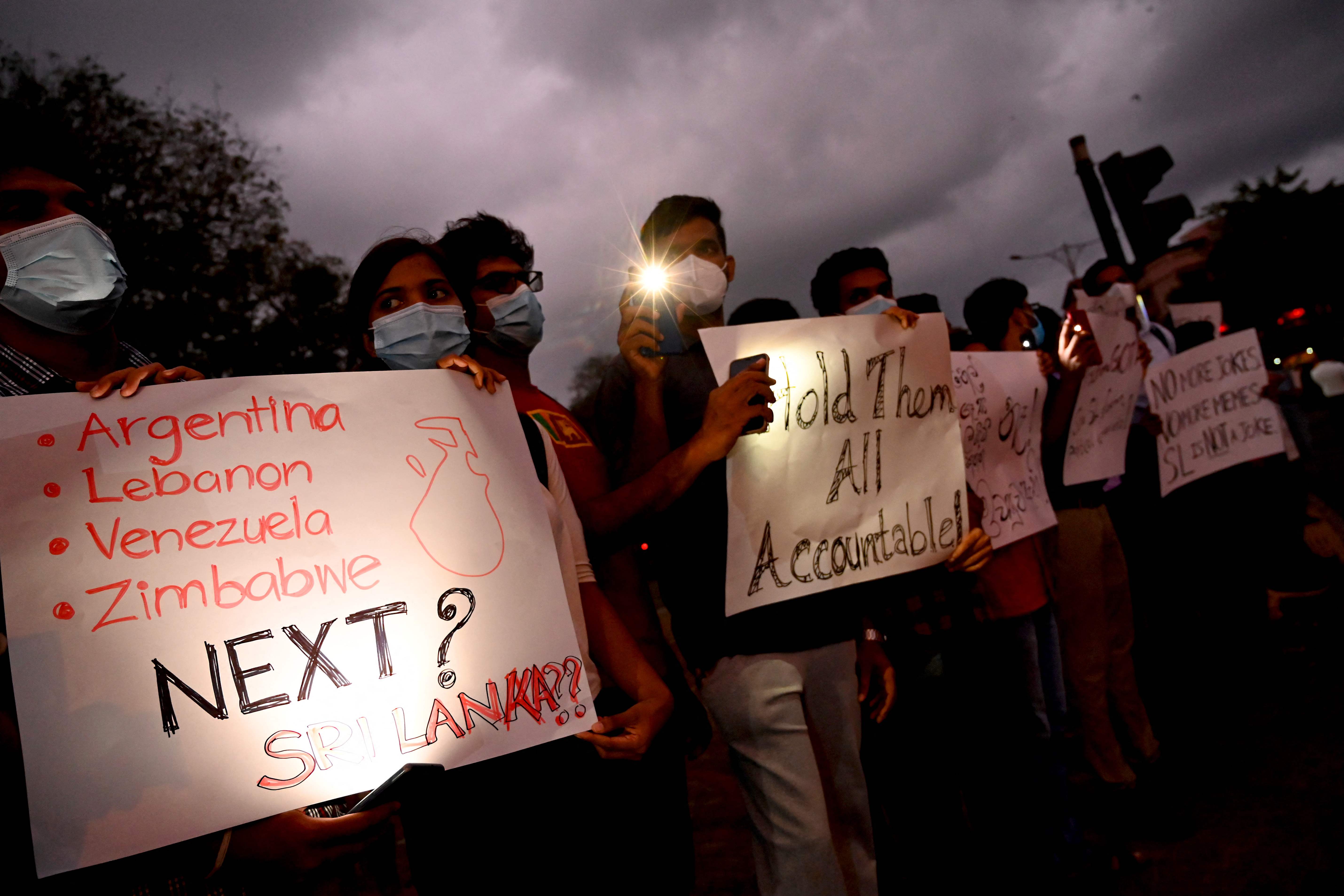 People hold placards during a demonstration against the shortage of cooking gas, fuel and rising prices of other essential commodities in Colombo on 30 March