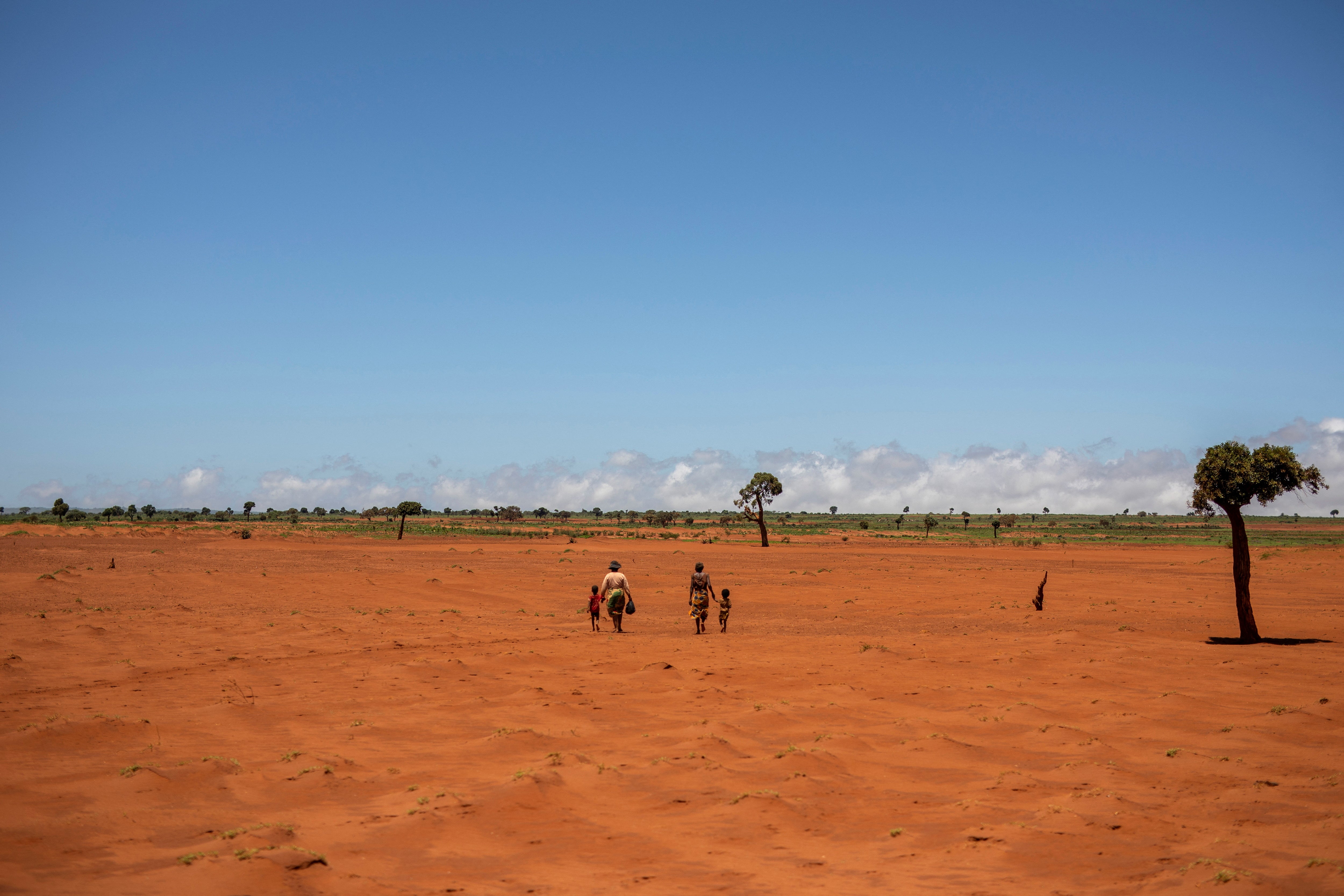 Tarira and her son Avoraza, four, walk through a field covered with red sand