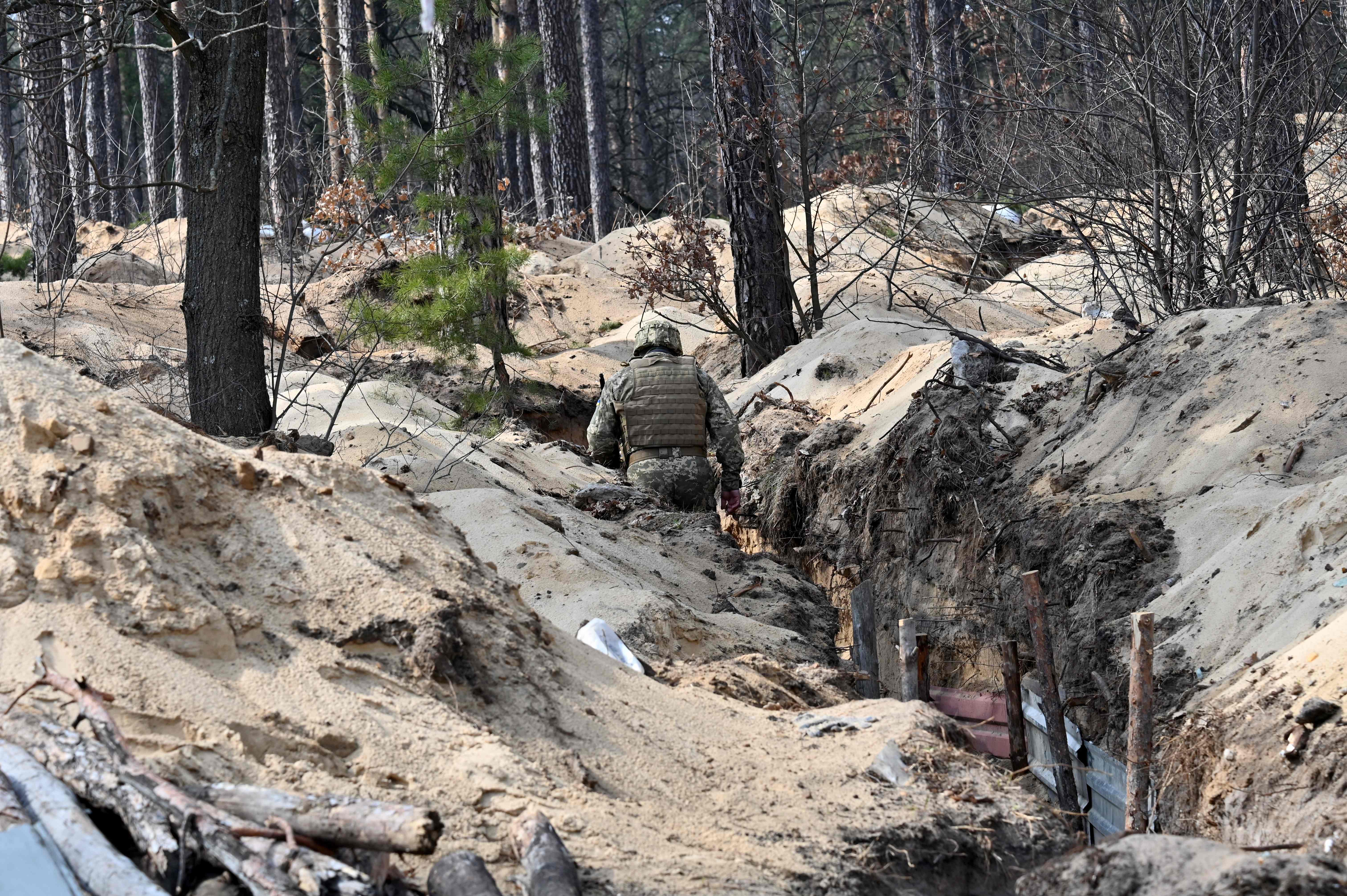 A Ukrainian serviceman walks along a trench on the front line, north of the capital of Kyiv