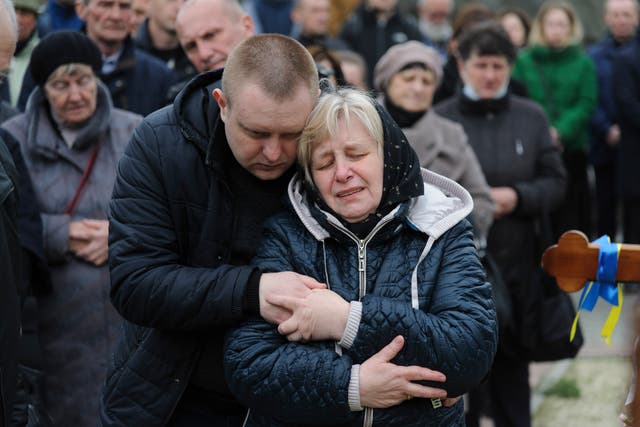 <p>Relatives are comforted during the funeral ceremony on Thursday of Ukrainian servicemen who died during the Russian invasion</p>