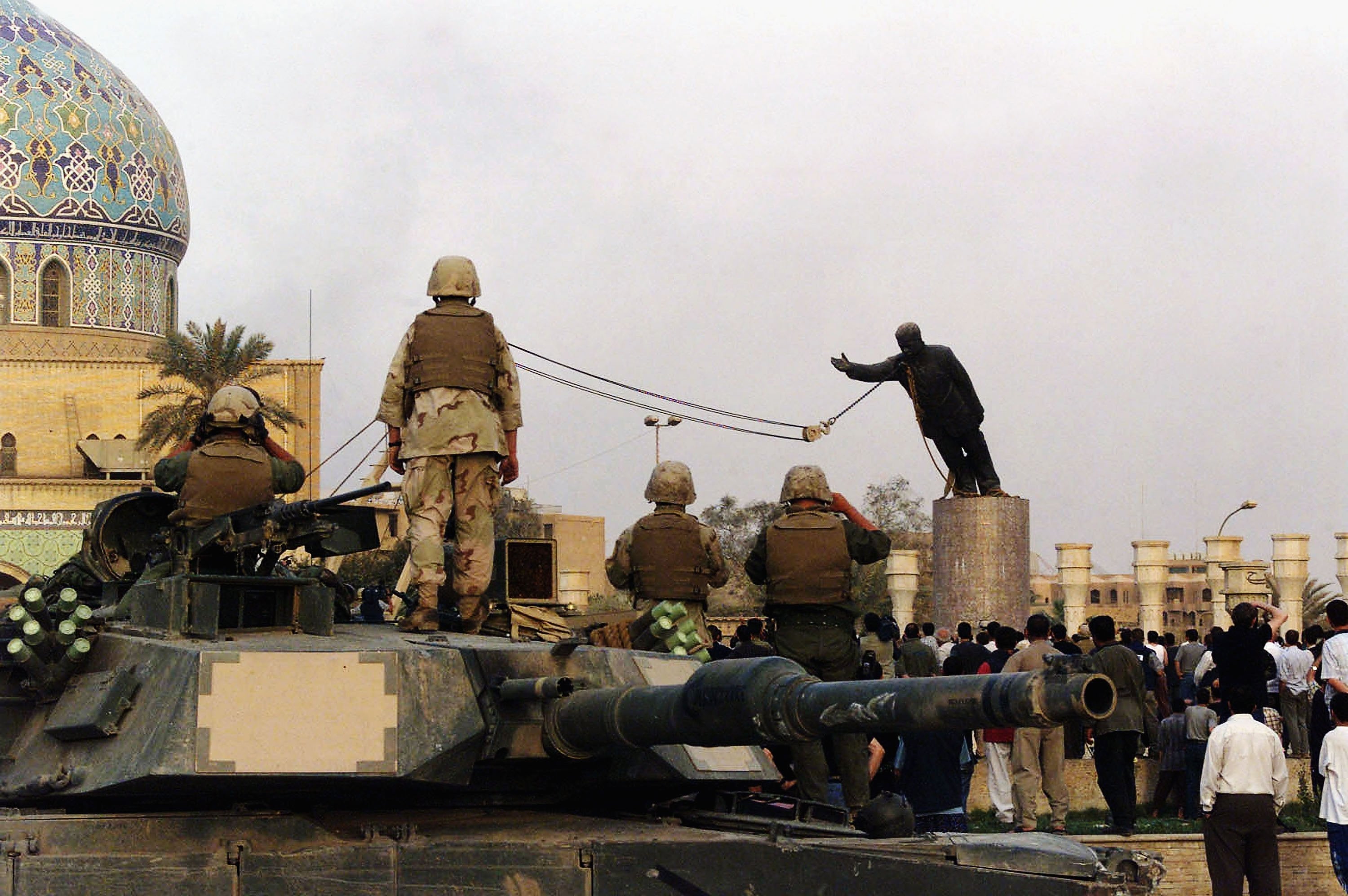 US marines and Iraqis are seen on 9 April 2003 as the statue of Iraqi dictator Saddam Hussein is toppled at al-Fardous square in Baghdad, Iraq